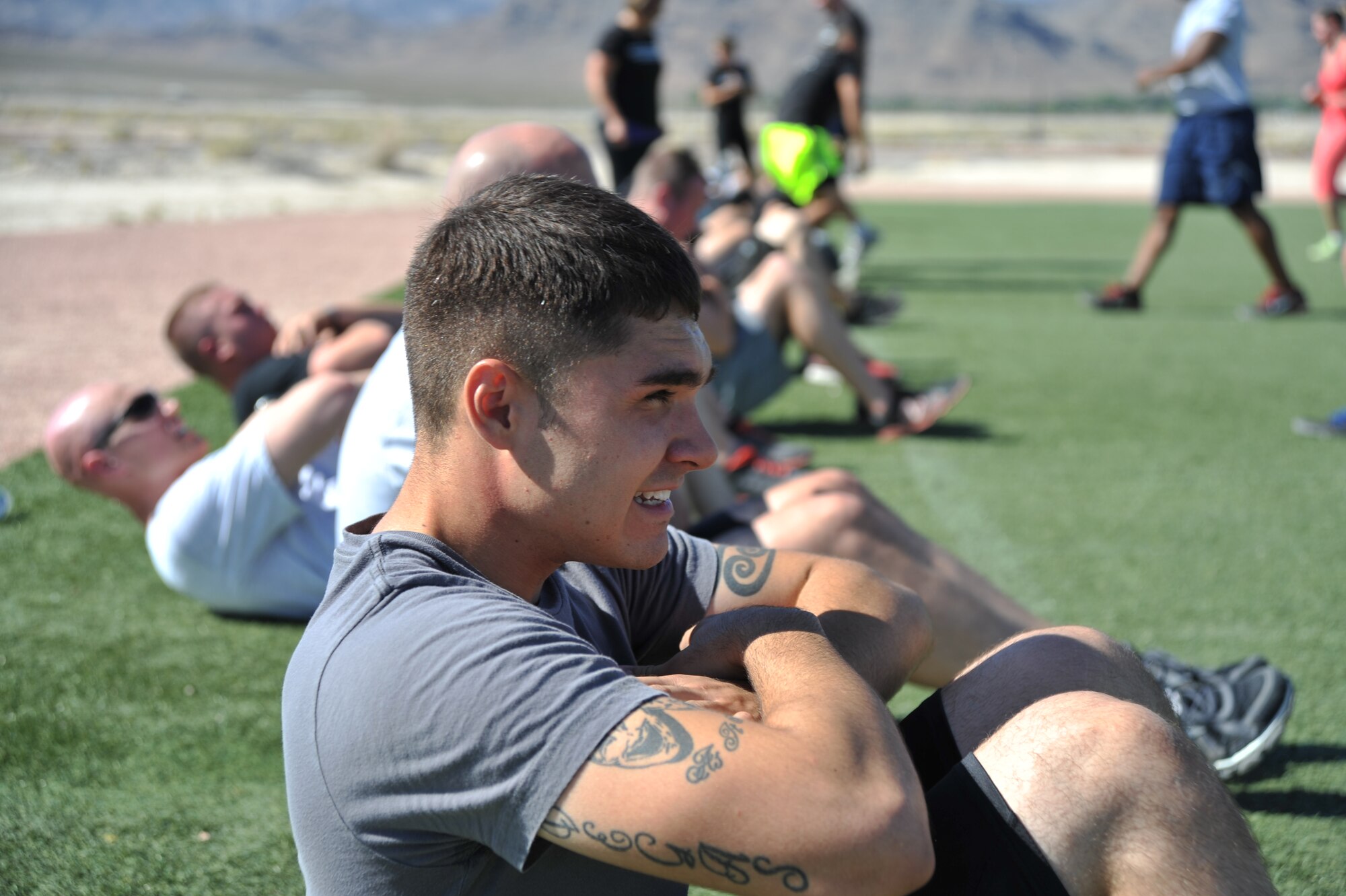 Senior Airman Quinn Turner, 799th Air Base Squadron vehicle maintainer, performs sit-ups alongside Creech Airmen during a Warrior Trained Fitness event June 23, 2014, at Creech Air Force Base, Nev. The Life of a Warrior campaign events focus on the whole-person concept to include the physical, mental, social and spiritual pillars of resiliency. (U.S. Air Force photo by Tech. Sgt. Shad Eidson/Released)
