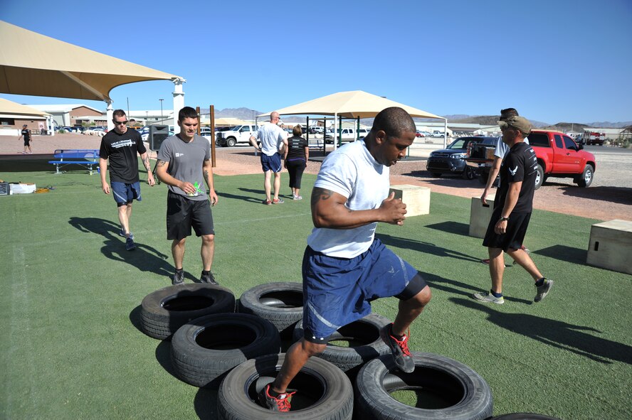 Creech Airmen perform high knees through a tire course during a Warrior Trained Fitness event June 23, 2014, at Creech Air Force Base, Nev. The Life of a Warrior campaign events are designed to take a motivational and practical approach of Airmen helping other Airmen seek excellence in the physical, spiritual, social and mental aspects of their lives. (U.S. Air Force photo by Tech. Sgt. Shad Eidson/Released)