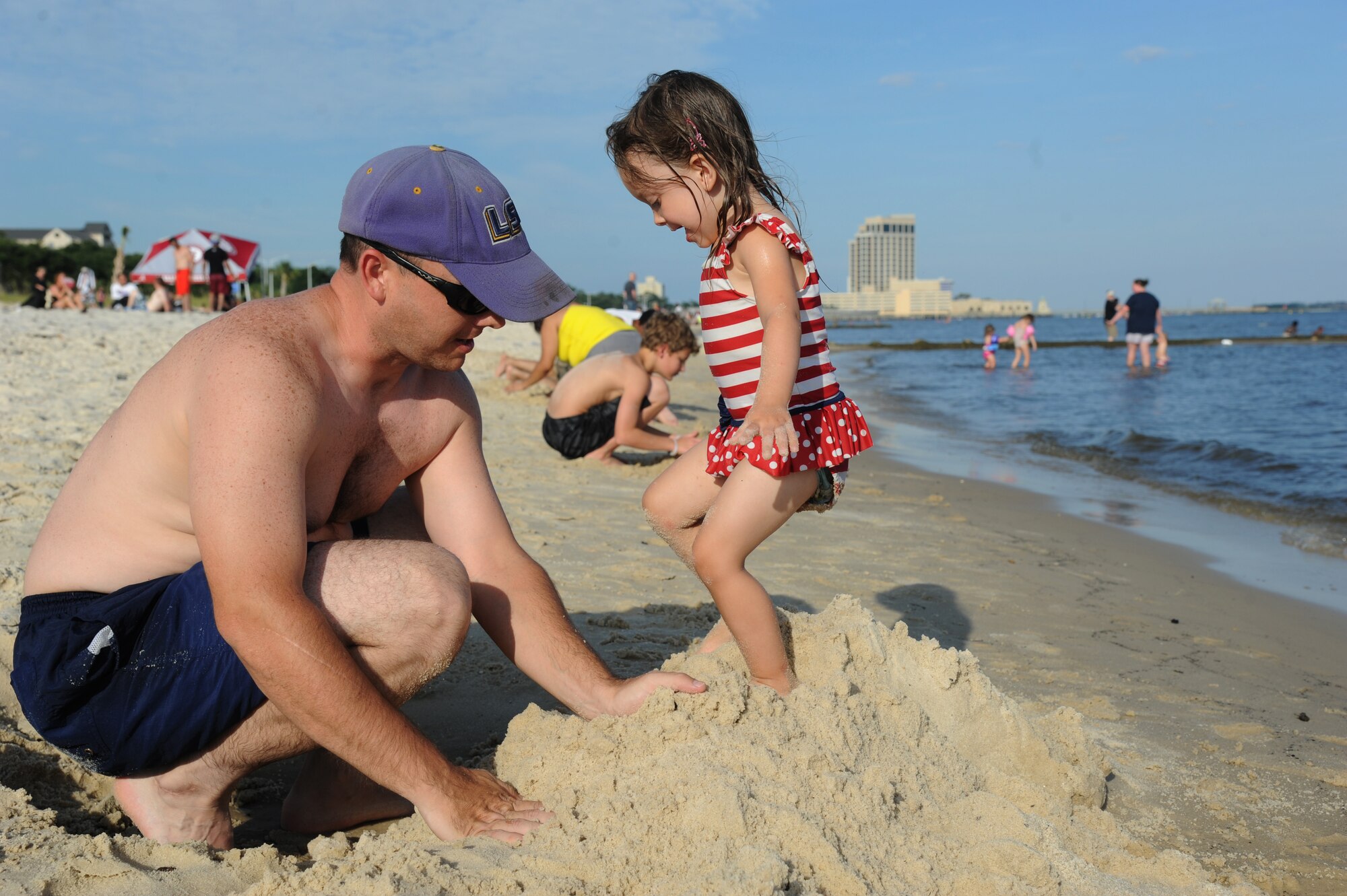 Tech. Sgt. Kyle Pourciau, Keesler firefighter, and his daughter collapse a sand castle during Keesler’s 4th of July Beach Bash on Biloxi Beach, Miss.  The event included contests, music, games, food and fireworks.  (U.S. Air Force photo by Kemberly Groue)