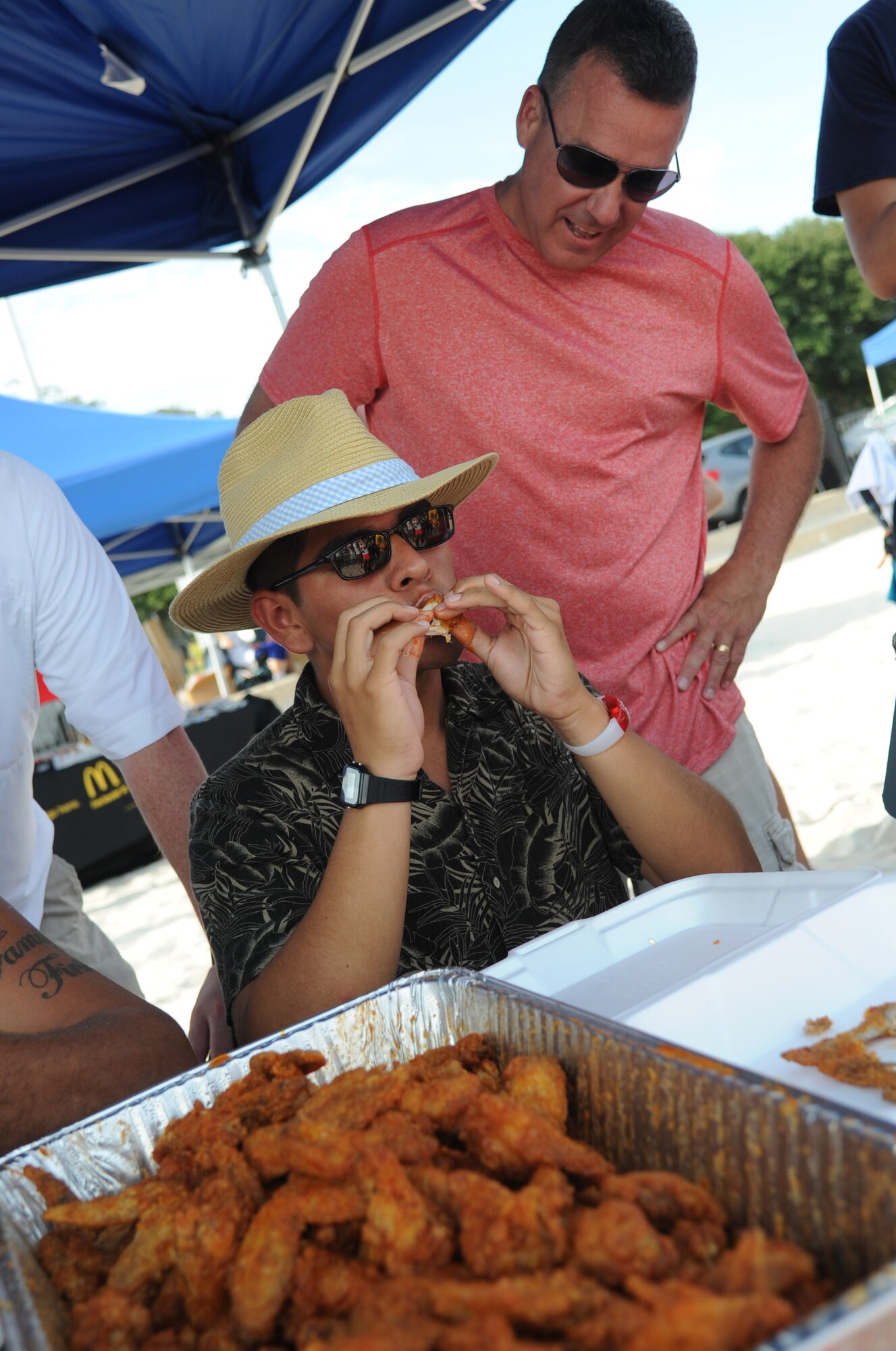 Airman Basic Jerry Jamaica, 338th Training Squadron, competes in the hot wing eating contest as Lt. Col. Jeffrey McLemore, 81st Training Group, keeps count during Keesler’s 4th of July Beach Bash on Biloxi Beach, Miss.  The event included contests, music, games, food and fireworks.  (U.S. Air Force photo by Kemberly Groue)