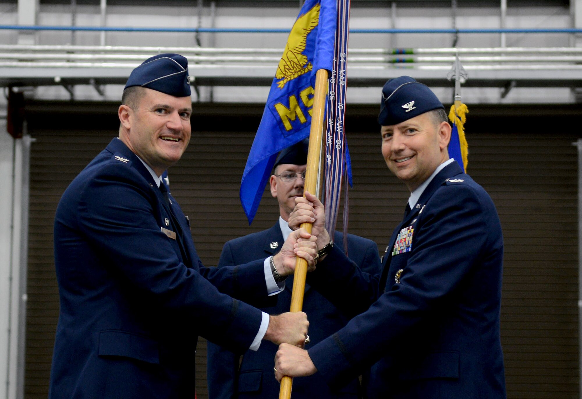 U.S. Air Force Col. Kenneth T. Bibb, Jr., left, 100th Air Refueling Wing commander, passes the guidon to U.S. Air Force Col. David Avila, 100th Mission Support Group commander, during the 100th MSG change of command July 8, 2014, on RAF Mildenhall, England. Avila assumed command from U.S. Air Force Col. Daniel Merry. (U.S. Air Force photo/Airman 1st Class Kyla Gifford/Released)