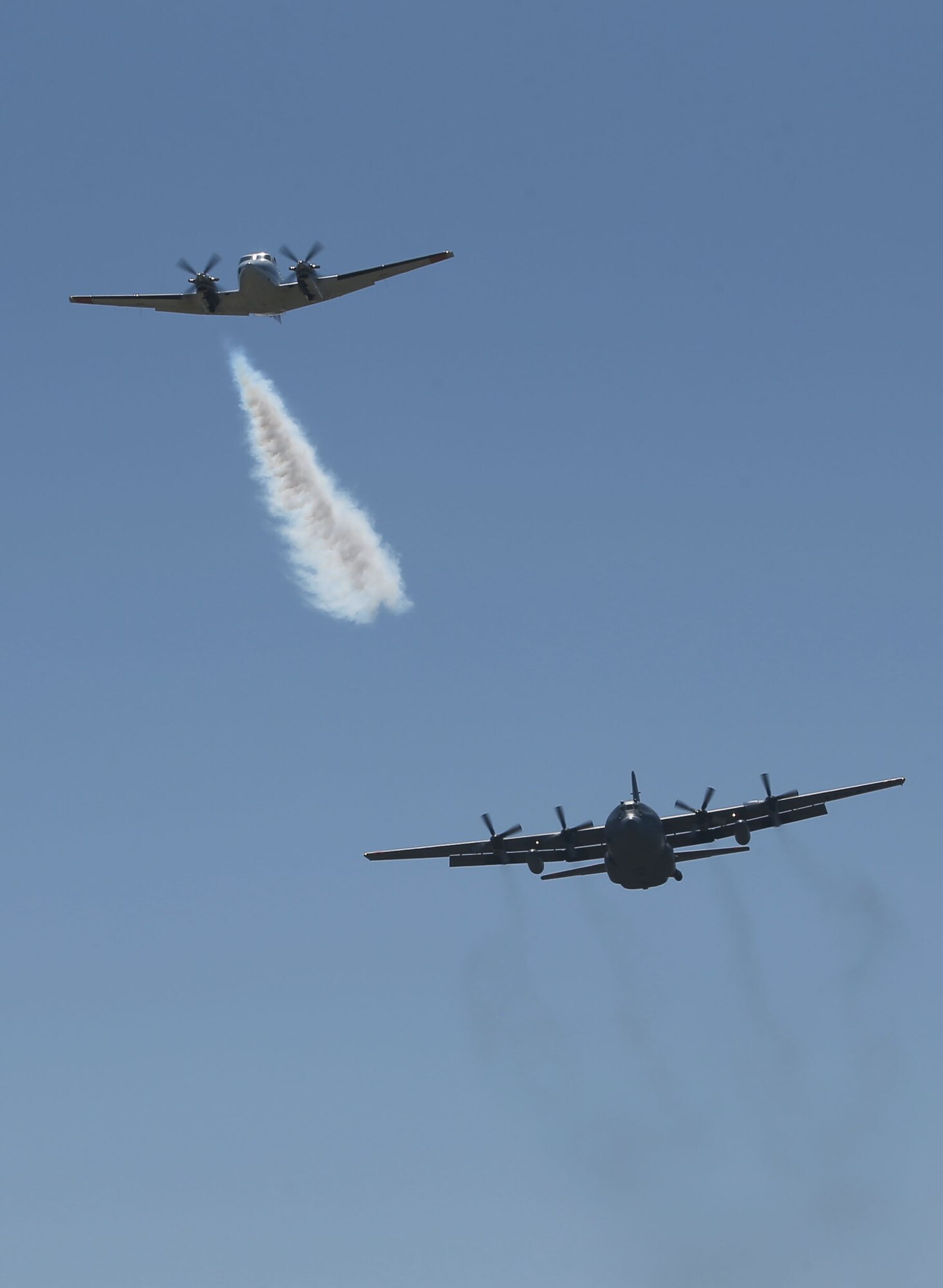 A U.S. Forest Service lead plane blows smoke to signal a Modular Airborne Fire Fighting System-equipped C-130 from the Wyoming Air National Guard's 153rd Airlift Wing that it’s time to drop its payload during annual MAFFS training, near Cheyenne, Wyo., on May 1, 2014. (Wyoming National Guard photo by Sgt. 1st Class Jimmy McGuire)

