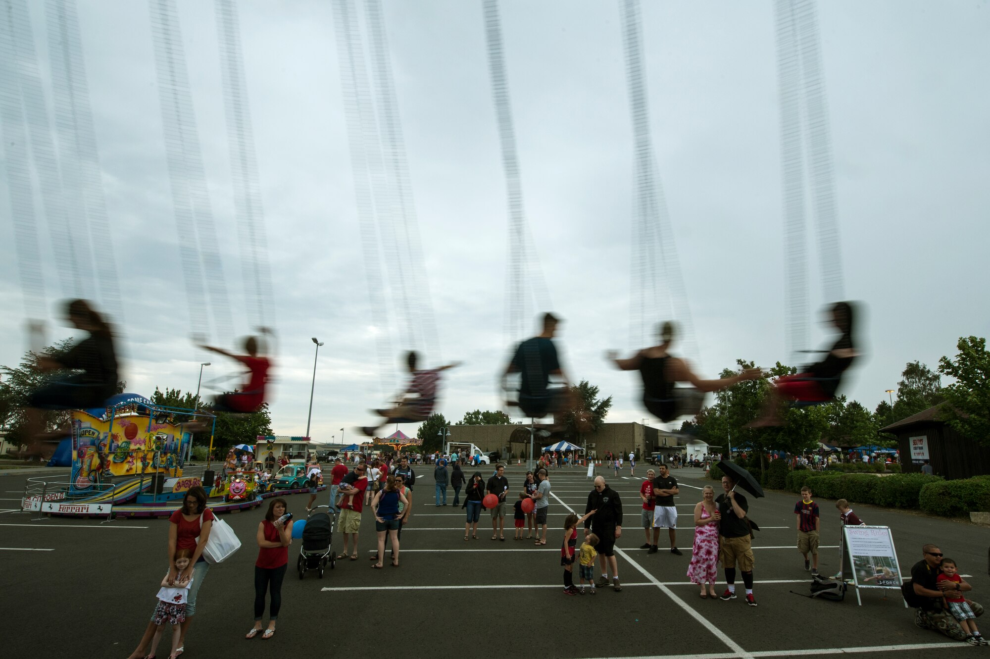 People ride a swing during Super Saber Appreciation Day July 4, 2014, at Spangdahlem Air Base, Germany. During the event, families could ride the swing, ride ponies and scale a climbing wall. (U.S. Air Force photo by Senior Airman Rusty Frank/Released))