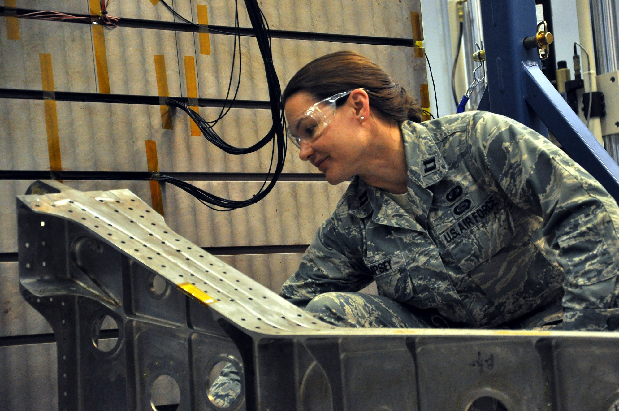 Capt. Allison Dempsey, Air Force Research Laboratory Aerospace Systems Directorate deputy branch chief, Wright-Patterson Air Force Base, Ohio, prepares for an experiment using the Structural Health Monitoring Test Bed. The SHM Test Bed enables AFRL researchers to investigate the performance of emerging instrumentation technologies for sensing fatigue cracking and strain in aircraft structures. In this experiment, a beam-like structure is being used as an analog for real aircraft structures. New instrumentation technologies will enable improved characterization of damage state and usage in aircraft structures. "The technology options AFRL provides give our warfighters an advantage on the battlefields of today and tomorrow,” said AFRL commander Maj. Gen. Thomas Masiello. “Those options help ensure we are on the right side of an unfair fight against America's adversaries, and it's our mission to keep it that way.” (Air Force photo by Michele Eaton)