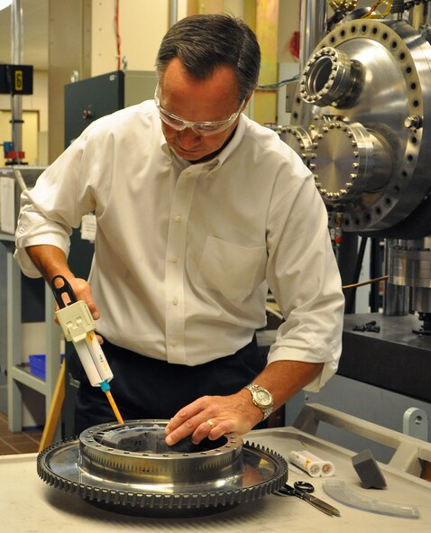 Jay Jira, Air Force Research Laboratory Materials and Manufacturing Directorate technology transition lead, Wright-Patterson Air Force Base, Ohio, applies replication material, often used by dentists, to make high resolution "images" of potentially damaged regions.  These replicas provide a way for Air Force maintainers to observe and measure features in hard to reach areas on the components. "The technology options AFRL provides give our warfighters an advantage on the battlefields of today and tomorrow,” said AFRL commander Maj. Gen. Thomas Masiello. “Those options help ensure we are on the right side of an unfair fight against America's adversaries, and it's our mission to keep it that way.” (Air Force photo by Michele Eaton)