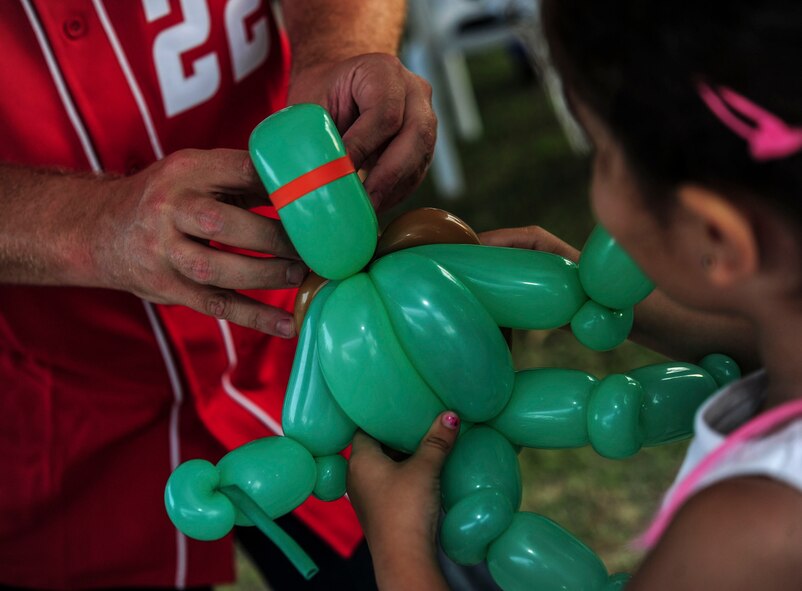 A balloon artist hands a "ninja-turtle" balloon to a child at the Independence Day celebration July 4, 2014,  Incirlik Air Base, Turkey.  More than 400 Airmen and family members attended the event. (U.S. Air Force photo by Senior Airman Nicole Sikorski/Released) 