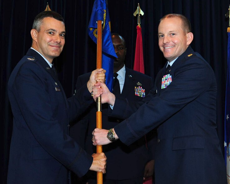 Col. Sean T. Gallagher, 39th Mission Support Group commander, passes the guidon to Maj. Bennet Burton, 39th Contracting Squadron incoming commander, during a change of command ceremony July 8, 2014, The passing of the guidon signified the transition of command from Maj. Wardrias Little to Burton. (U.S. Air Force photo by Staff Sgt. Eboni Reams/Released)