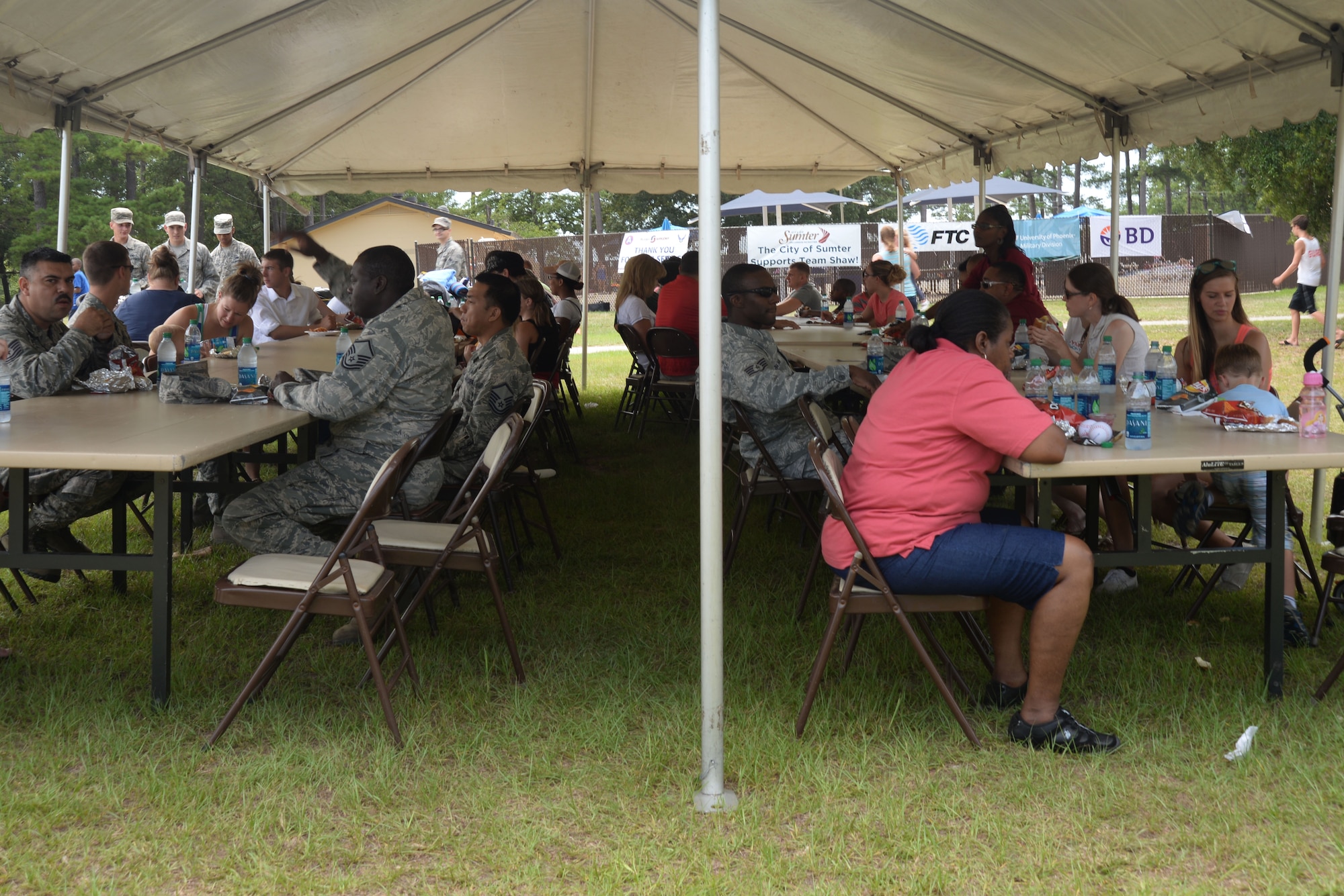 Members of Team shaw eat food during the 20th Force Support Squadron Freedom Bash at Shaw Air Force Base, South Carolina, July 3, 2014. The 20th FSS cooked hamburgers, hot dogs, and bratwursts which were free for all military and civilian identification card holders and their families. (U.S. Air Force photo by Airman 1st Class Michael A. Cossaboom/Released)