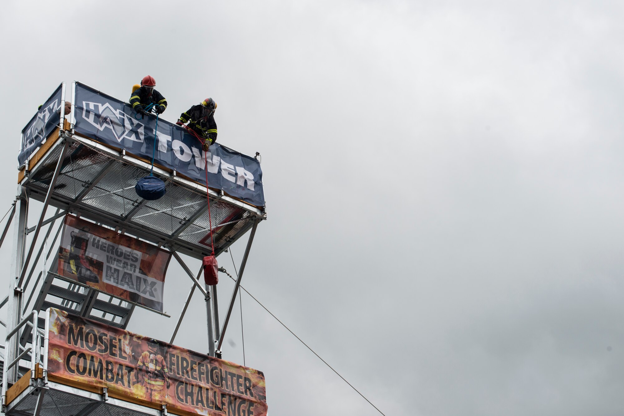 U.S. Air Force Airman 1st Class Scott Weeks, 52nd Civil Engineer Squadron firefighter from Green Bay, Wis., and Palvic Andraz, a firefighter from Bequnje Ha Gorenjskem, Slovakia, hoists a 40-pound weight at the first Mosel Firefighter Combat Challenge in Ediger-Eller, Germany, July 5, 2014. Hoisting the weight simulates pulling tools or an additional hose from a building roof to combat a fire. (U.S. Air Force photo by Staff Sgt. Christopher Ruano/Released)