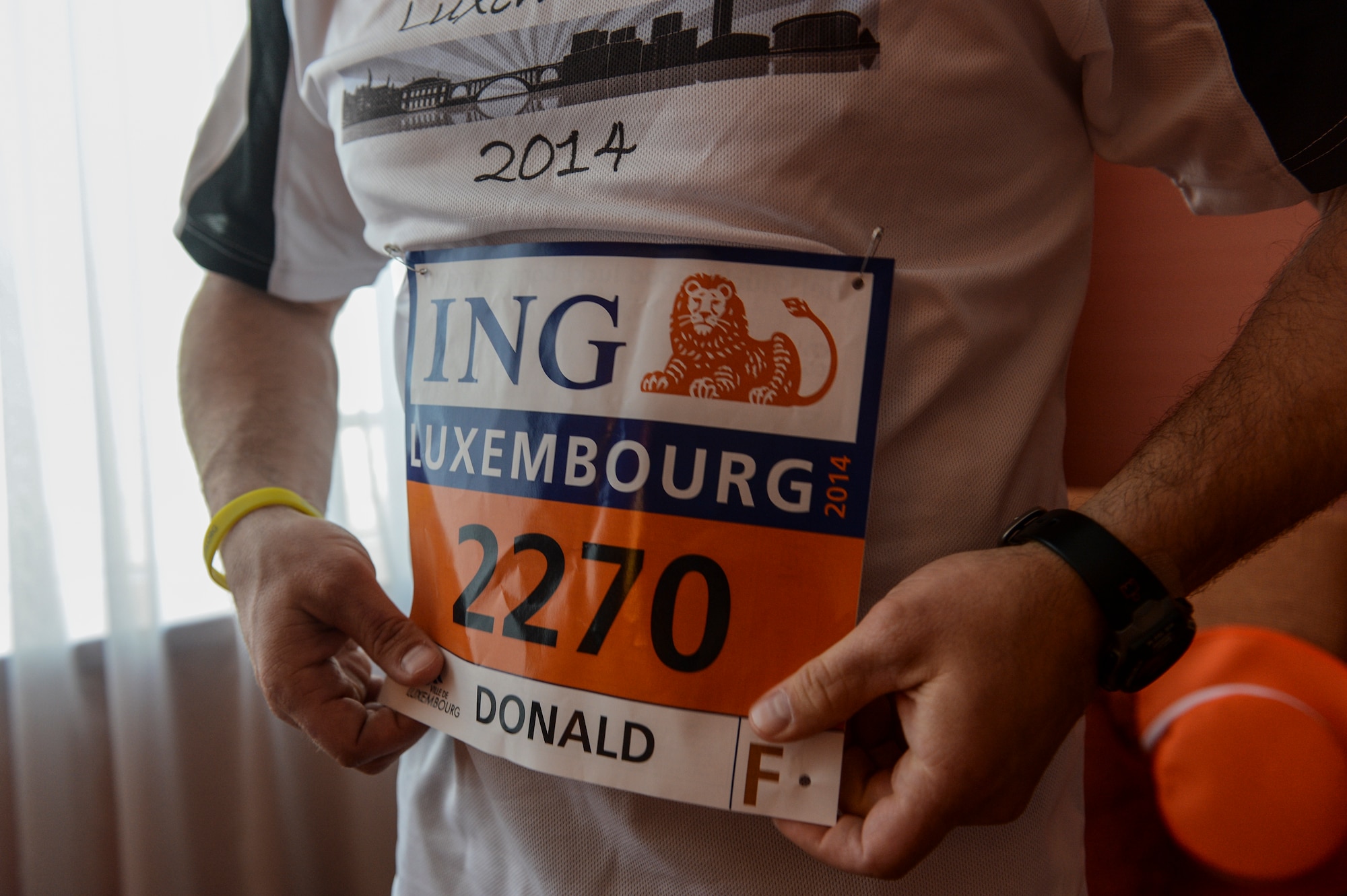 U.S. Air Force Master Sgt. Donald Stichter, 52nd Equipment Maintenance Squadron NCO in charge of munitions inspection from Lakewood, Colo., tacks his number to a shirt prior to the start of the ING Luxembourg Night Marathon May 31, 2014, in Luxembourg. More than 9,000 people competed in the race. (U.S. Air Force photo by Senior Airman Rusty Frank/Released)