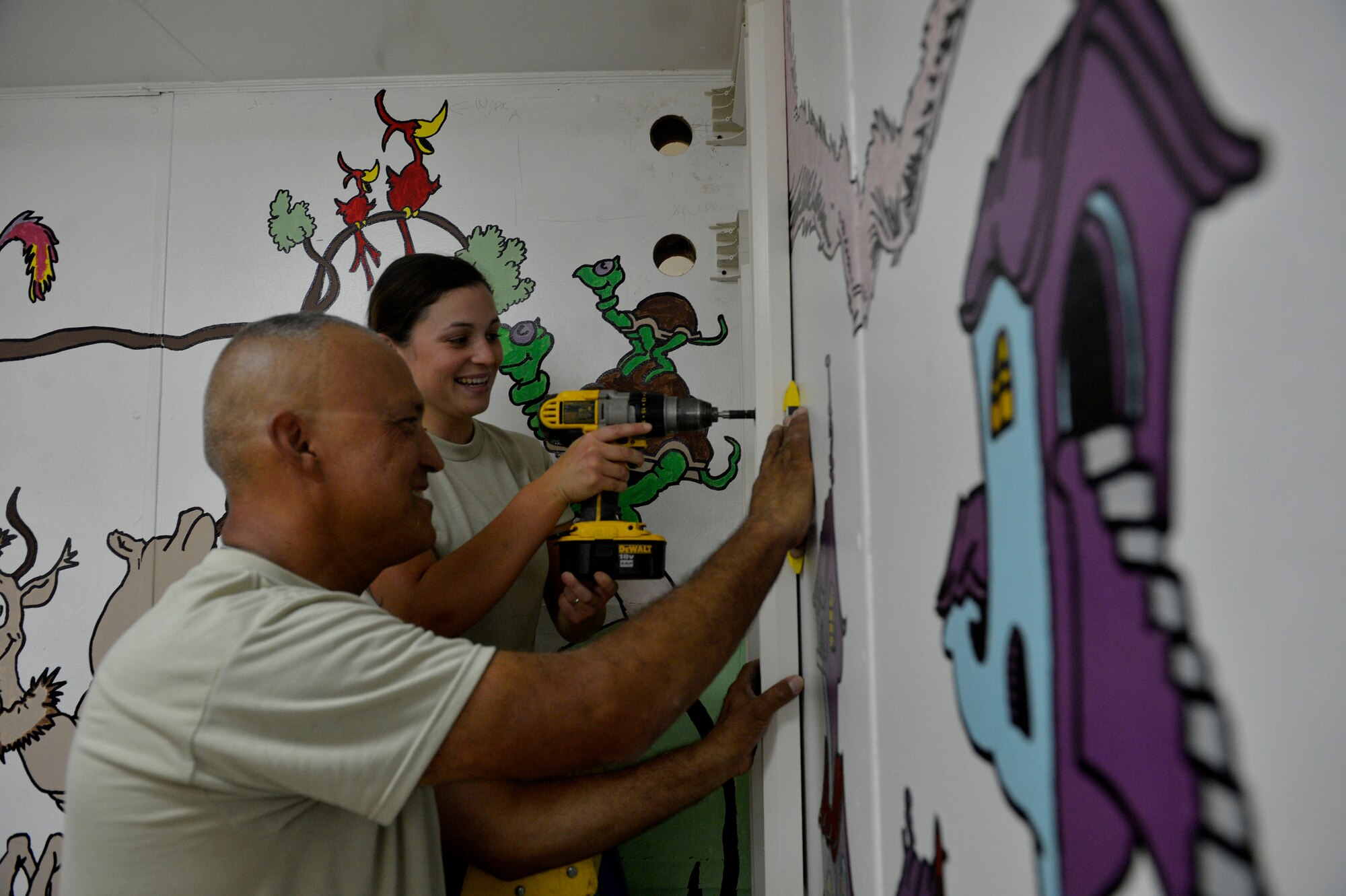 (From left) Tech. Sgt. John Trujillo and Staff Sgt. Kimberly Buzzell, drill a hole on a wall to install cables at Bagram Airfield, Afghanistan July 1, 2014.  Trujillo and Buzzell are father and daughter, both assigned to Task Force Signal and deployed from the Air National Guard’s 243rd Engineering Installation Squadron in South Portland, Maine and natives of Turner, Maine. Trujillo is a cable and antenna team chief while Buzzell is a radio frequency transmissions technician.  (U.S. Air Force photo by Staff Sgt. Evelyn Chavez/Released)