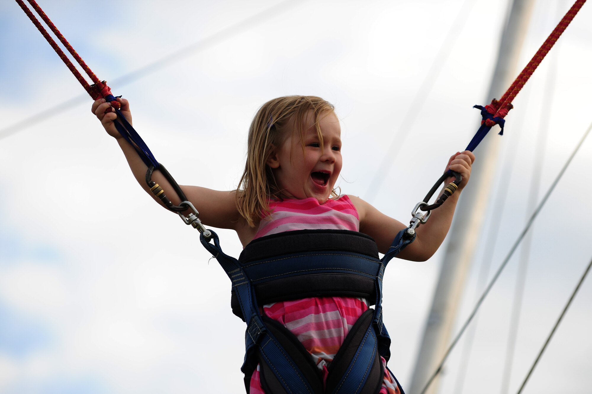 A young girl jumps high into the air on a bungee trampoline at the Fourth of July celebration on RAF Alconbury, United Kingdom, July 3, 2014. Children were able to enjoy numerous attractions at the festival. (U.S. Air Force photo by Staff Sgt. Jarad A. Denton/Released)