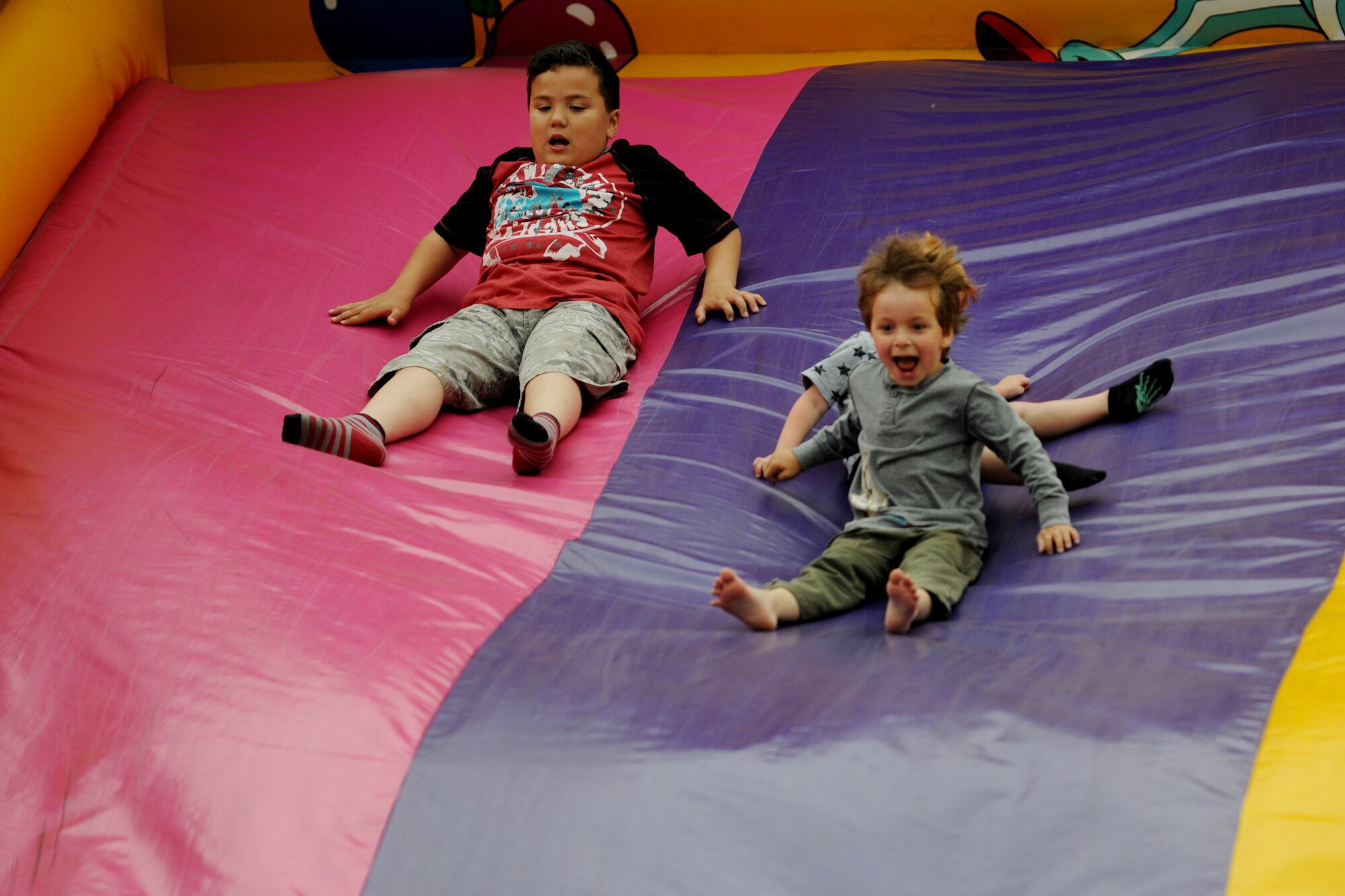 Children propel down an inflatable slide during the Fourth of July celebration at RAF Alconbury, United Kingdom, July 3, 2014. During the festival, military families were able to interact with members of the local community. (U.S. Air Force photo by Staff Sgt. Jarad A. Denton/Released)