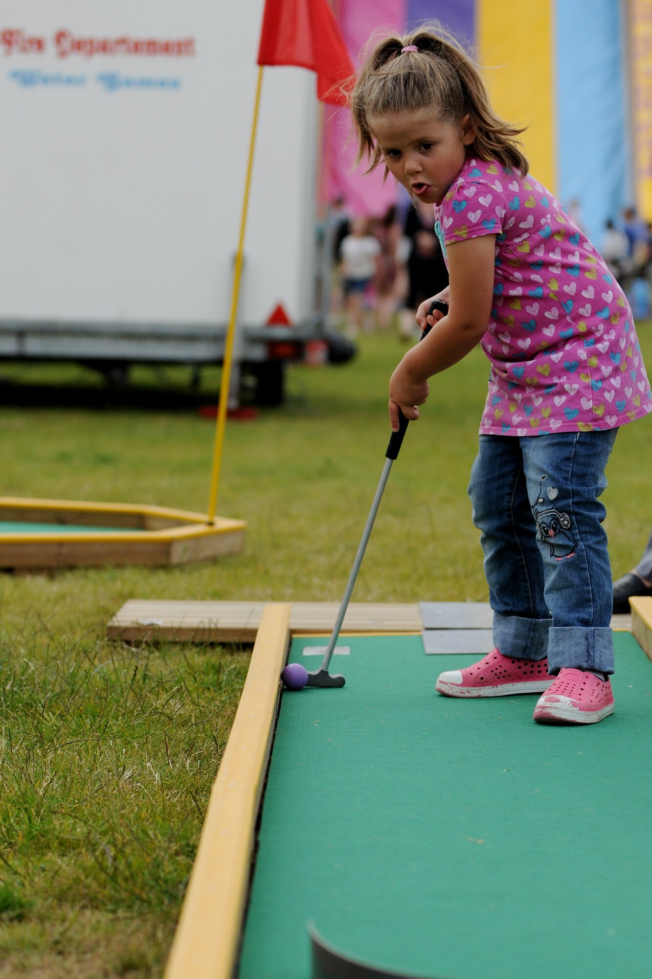 A young girl putts a mini-golf ball toward the cup at the Fourth of July celebration on RAF Alconbury, United Kingdom, July 3, 2014. The 501st Combat Support Wing celebrated Independence Day by opening the base for military and local community families to enjoy the festivities. (U.S. Air Force photo by Staff Sgt. Jarad A. Denton/Released)