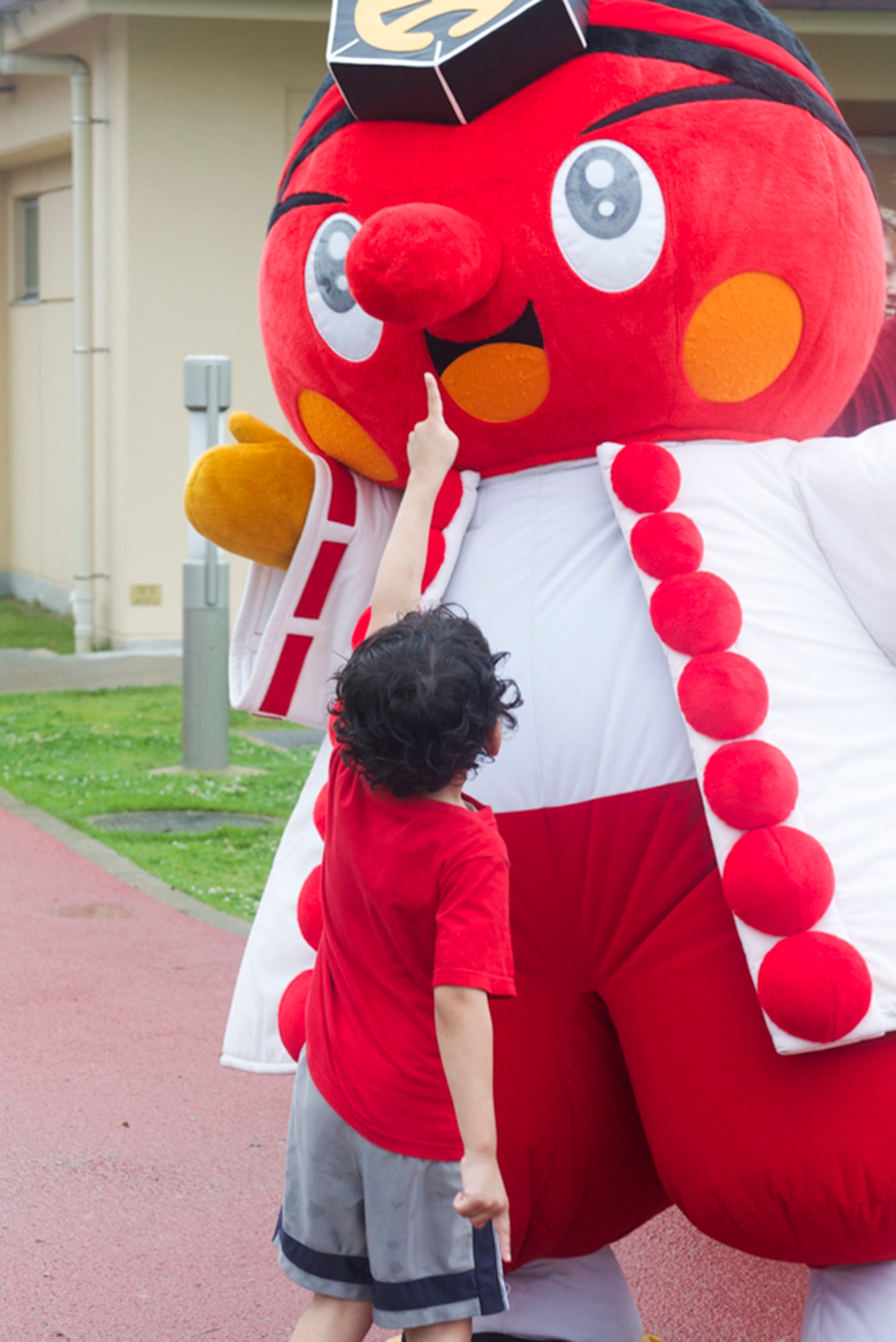 A child attempts to touch Tengu's nose during the Celebrate America event hosted by the 374th Force Support Squadron at Yokota Air Base, Japan, July 4, 2014. Tengu is a deity from Japanese mythology and the mascot for the local city of Hachioji. (U.S. Air Force photo by Airman 1st Class David Danford/Released)