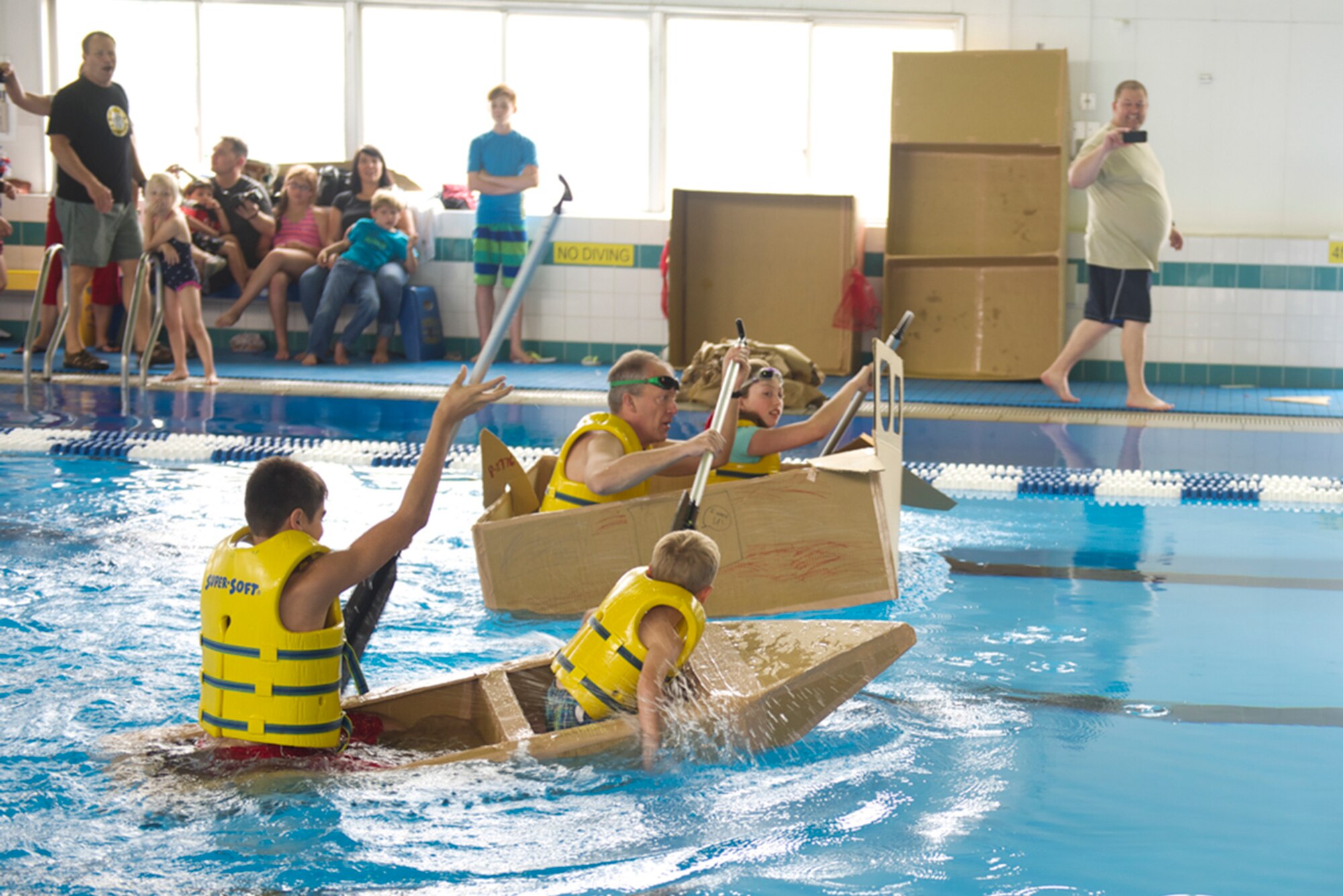 Two teams race toward the finish line in their cardboard boats during the Leaky Kon Tiki race at Yokota Air Base, Japan, July 4, 2014. In addition to the race the 374th Force Support Squadron hosted events throughout the day to include a 5k Fun Run, go-karts, carnival booths and performances from the Band of the Pacific-Asia Pacific Trends and the Bon Jovi tribute band, Slippery When Wet. (U.S. Air Force photo by Airman 1st Class David Danford/Released)