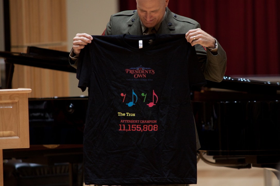 Principal horn Master Gunnery Sgt. Max Cripe calculated the number of after beats Master Gunnery Sgt. Troxel most likely played during his 30 years and presented him with a t-shirt bearing the number: 11,155,808. (U.S. Marine Corps photo by Staff Sgt. Brian Rust/released)