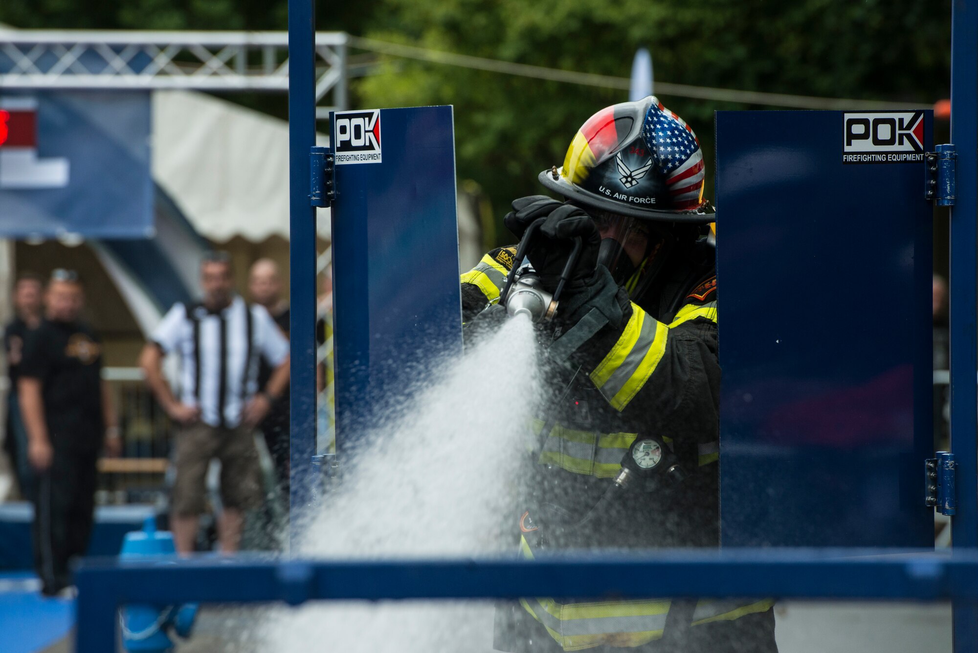Senior Master Sgt. Jason Theriault sprays water to extinguish a simulated fire at the first Mosel Firefighter Combat Challenge July 5, 2014, in Ediger-Eller, Germany. Theriault, a 52nd Civil Engineer Squadron deputy fire chief and a native of Gloucester, Mass., carried hose 78 feet crossed a simulated door to a building and turned on the hose to extinguish the fire. (U.S. Air Force photo/Staff Sgt. Christopher Ruano)