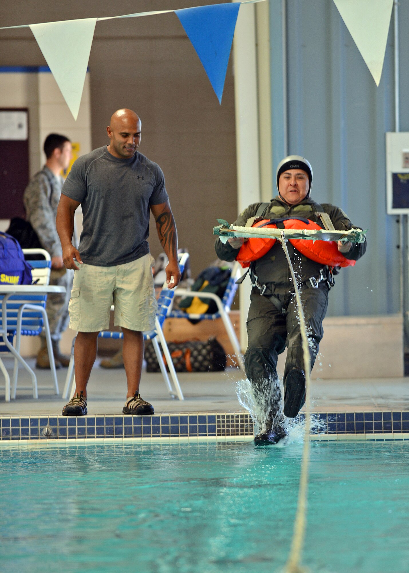 Orlando Canchola (right), honorary commander’s guest, undergoes a simulated parachute drag in water, July 2 in a land and water survival training class taught by Edwards Survival, Evasion, Resistance, and Escape instructors at the Oasis Aquatic Center. The simulated parachute drag in water teaches aircrew how to release from their parachute harness. The primary objective of the Honorary Commanders Program is to familiarize community leaders with Edwards' operations by pairing them with unit commanders and directors at both social and official functions. (U.S. Air Force photo by Jet Fabara)