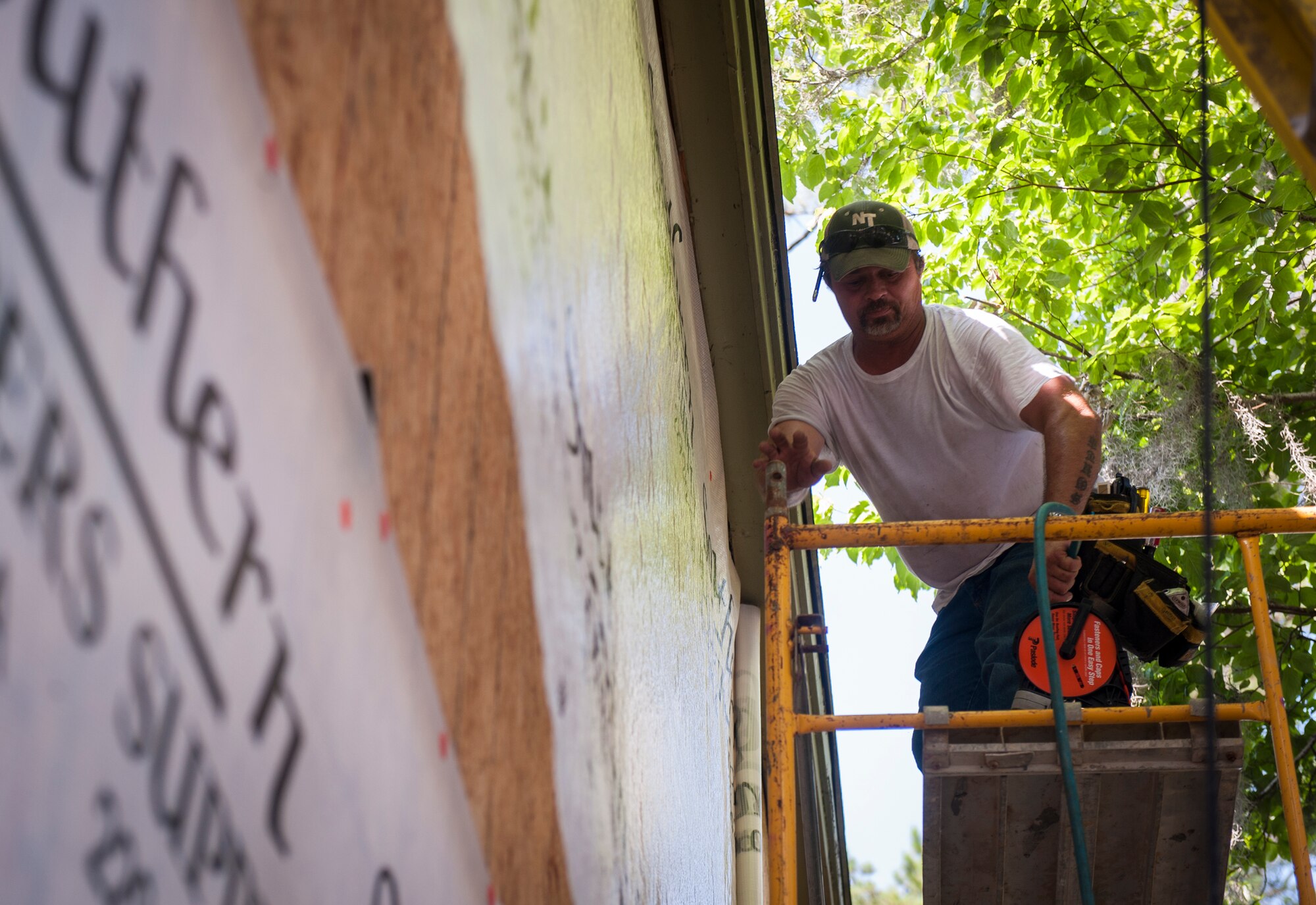 A contractor unravels a sheet of plastic on a former Moody Field Club building at Moody Air Force Base, Ga., July 1, 2014. The contractors have been working on the building for more than seven months to restore it to its original state. (U.S. Air Force photo by Senior Airman Jarrod Grammel/Released)
