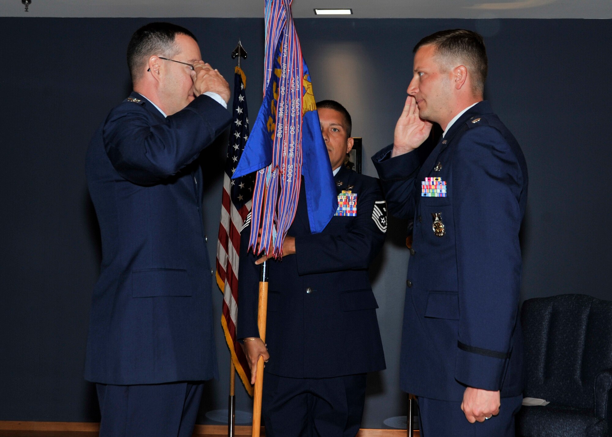 Colonel Christopher Holmes, 325th Mission Support Group commander, and Lt. Col. Richard Martin who assumed command of the 325th CES salute each other during in the change of command ceremony July 9 at the Horizons Community Center as Master Sgt. Jose Santiago, 325th CES first sergeant, looks on. (U.S. Air Force photo by Airman 1st Class Sergio Gamboa)