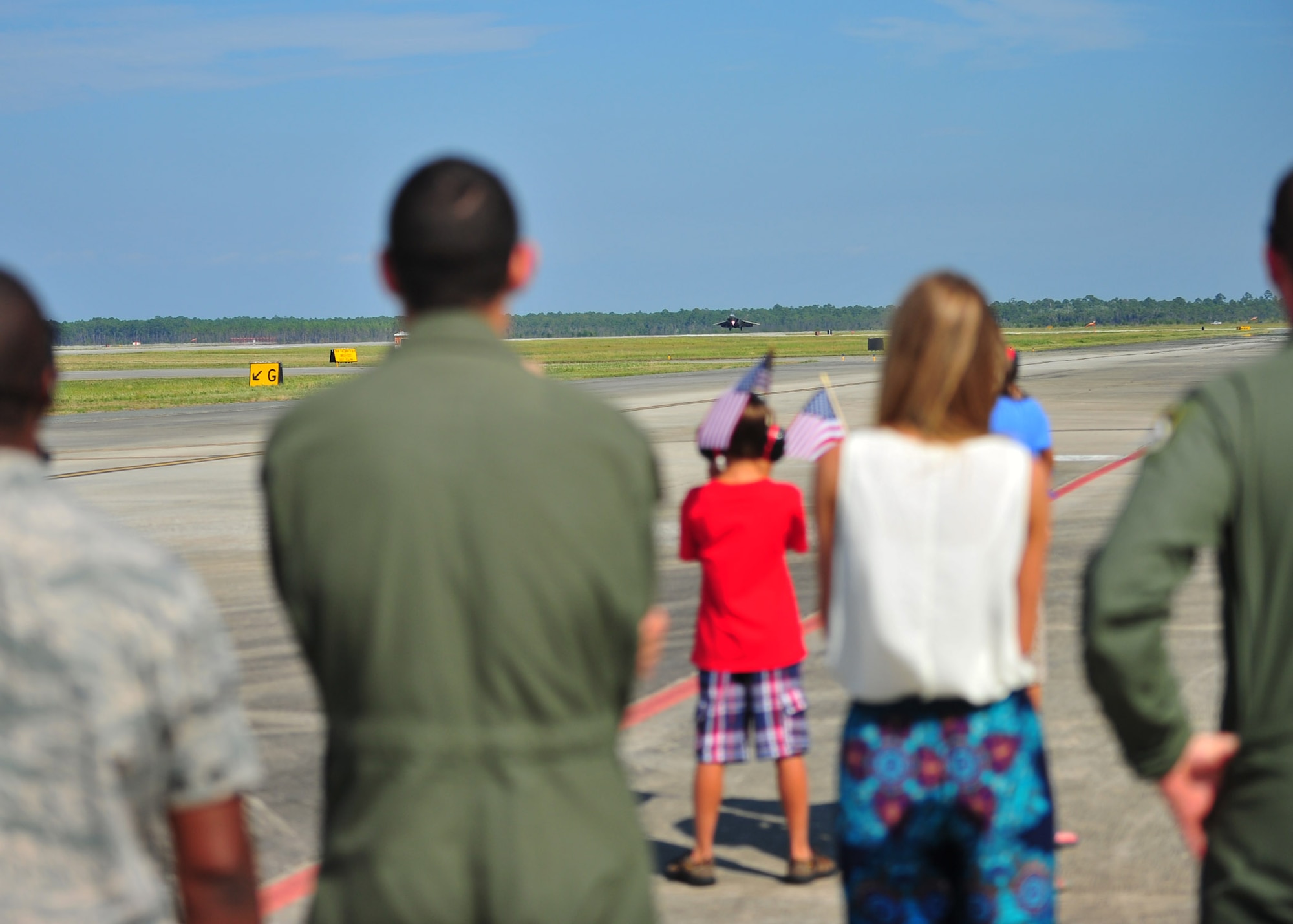 Family and friends of Maj. Daniel “Magic” Lee, 43rd Fighter Squadron instructor pilot, stand on the Tyndall flight line July 8 as he lands an F-22 Raptor. Lee reached his 1,000th hour logged in this aircraft, becoming only the fifth person in Air Force history to achieve this. (U.S. Air Force photo by Airman 1st Class Dustin Mullen)