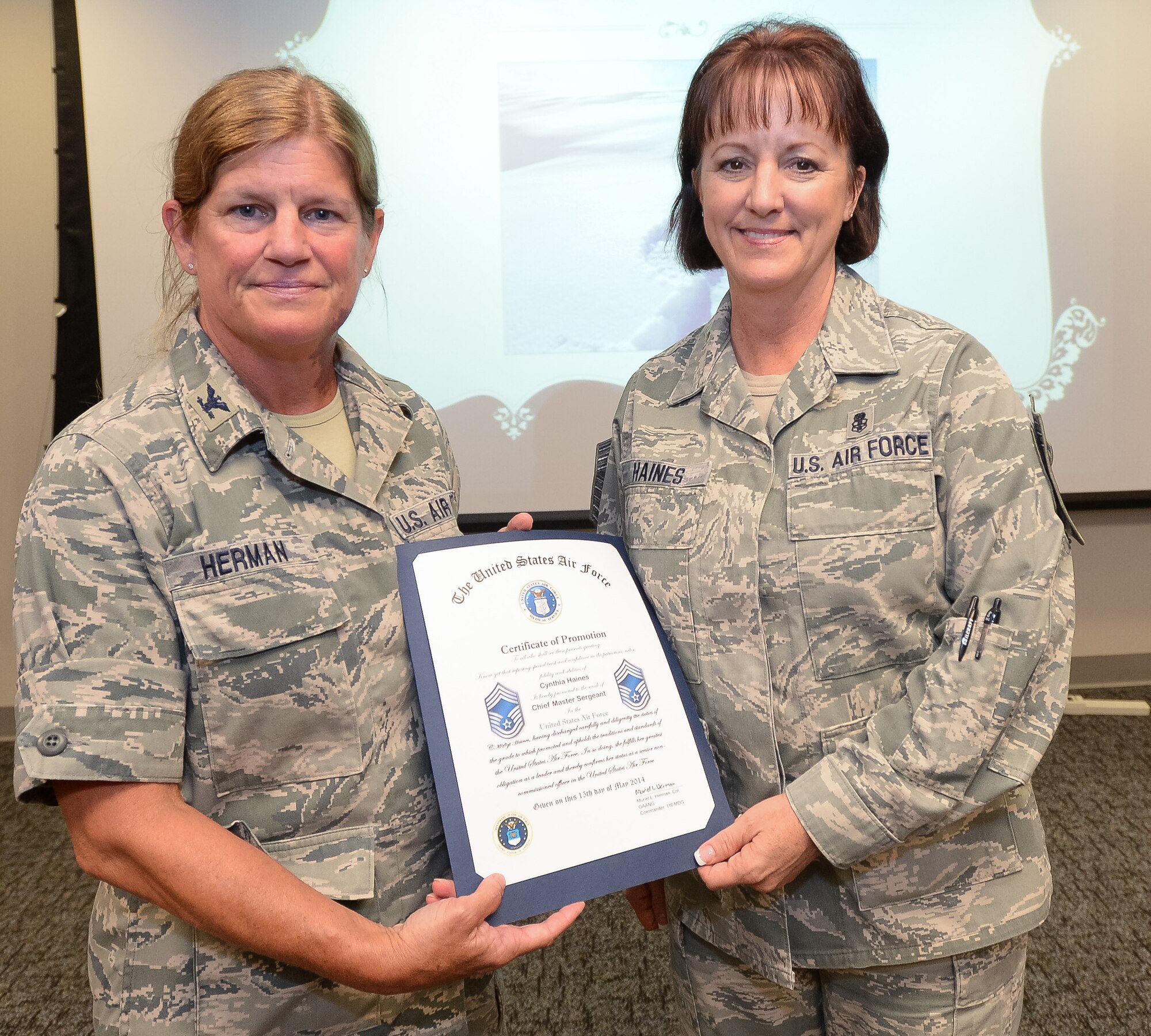 U.S. Air Force Col. Muriel Herman, 116th Medical Group (MDG) commander, Georgia Air National Guard, presents Chief Master Sgt. Cynthia Haines a certificate of promotion to the rank of Chief Master Sgt., Robins Air Force Base, Ga., June 21, 2014. Haines became the first female to be promoted to Chief Master Sgt. in the history of the 116th MDG. The 116th MDG is the medical arm of the 116th Air Control Wing.  (U.S. Air National Guard photo by Master Sgt. Roger Parsons/Released)

