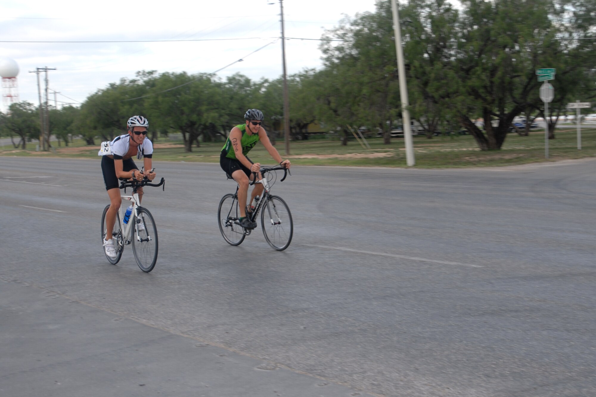 GOODFELLOW AIR FORCE BASE, Texas –  Two 2013 Annual Triathlon participants ride down Knickerbocker Road during the bicycle leg of the triathlon July 27. When riding a bicycle, riders are to follow driving rules, including stopping at red lights and stop signs. (U.S. Air Force photo/ Airman 1st Class Breonna Veal)