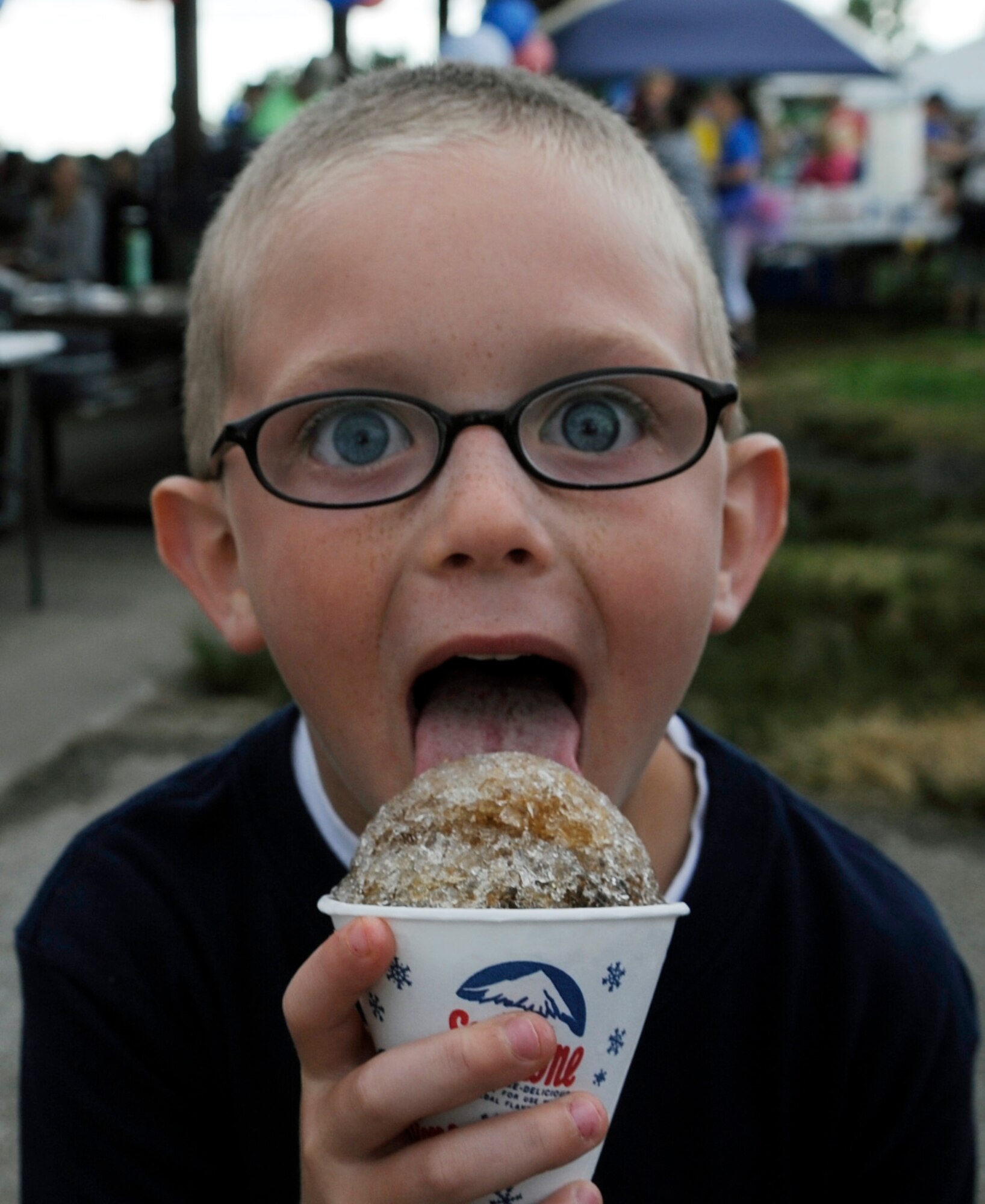 Ayden Fitte, licks a snow cone at the Independence Day Celebration at Whiteman Air Force Base, Mo., July 2, 2014. Airman and their families were able to purchase food and drinks at the celebration with games and activities free for fun. Evan is the son of Tech. Sgt. Robert Fitte, 509th Civil Engineer Squadron unit deployment manager. (U.S. Air Force photo by Staff Sgt. Alexandra M. Boutte/Released)