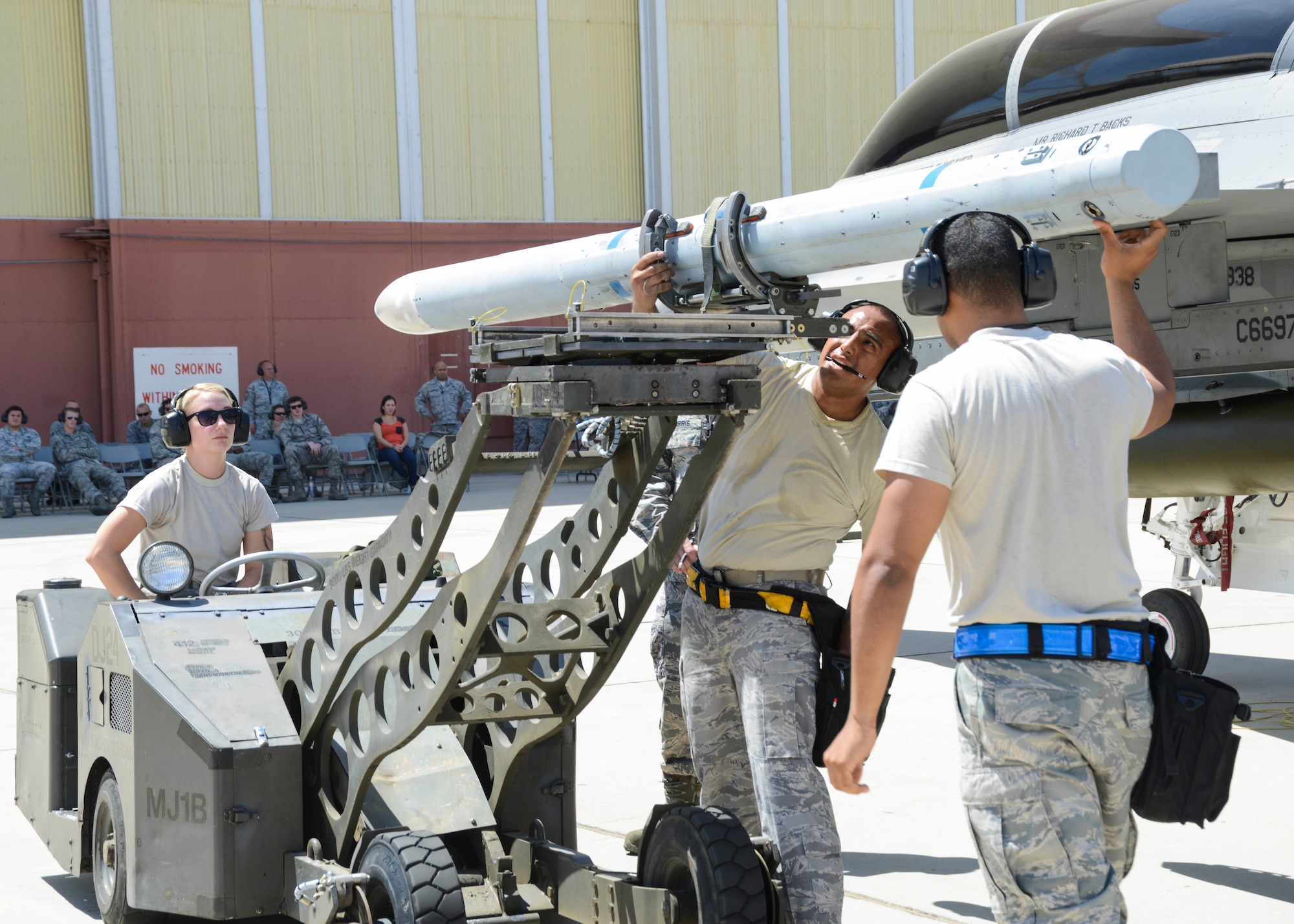The 445th AMU loads an AIM-120 to the outside rails of the F-16 as fellow maintainers look on. (U.S. Air Force photo by Rebecca Amber) 