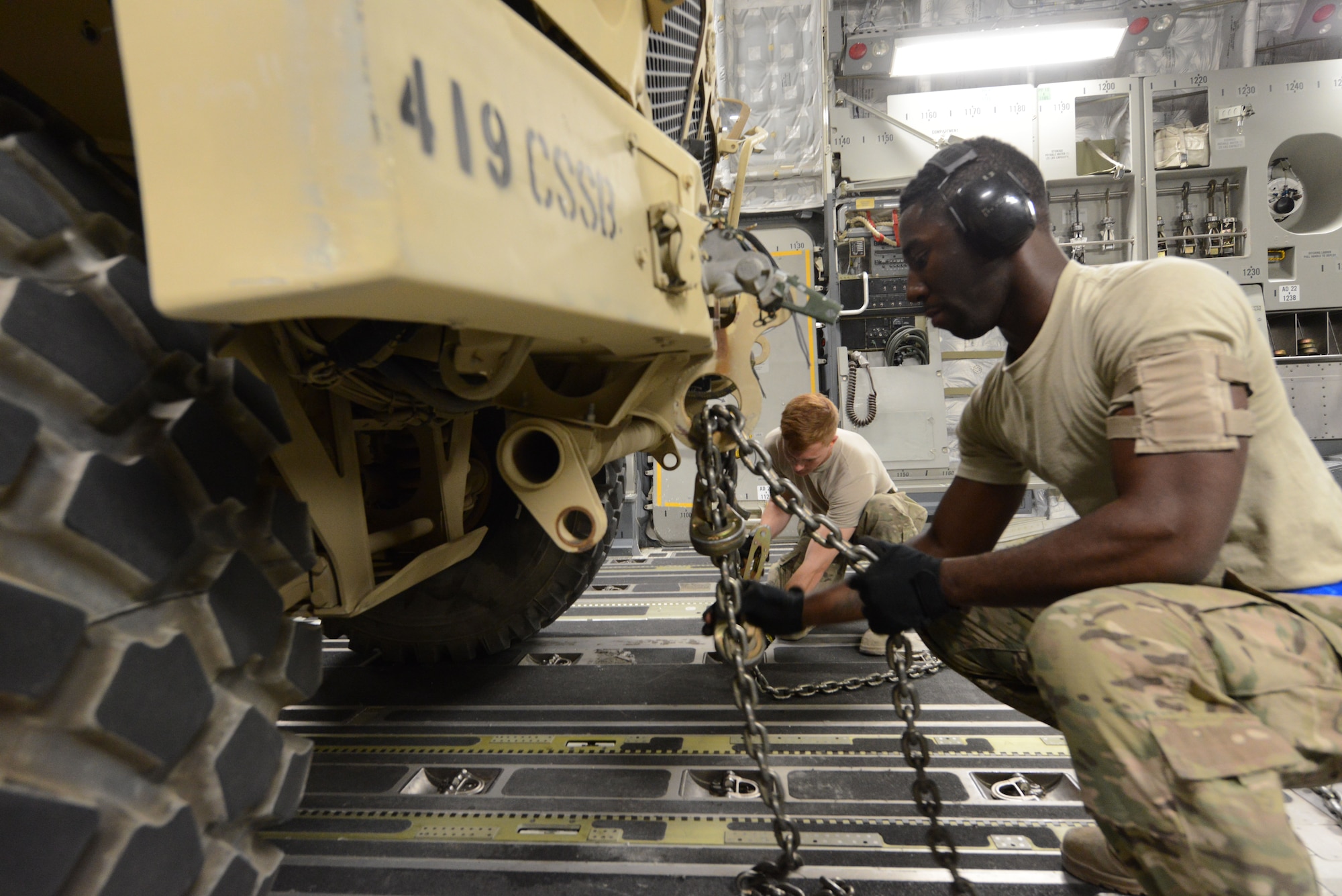 U.S. Air Force Senior Airman Nathaniel Hand and Airman 1st Class Marco Bouknight begin locking a Heavy Expanded Mobility Tactical Truck in place aboard a C-17 Globemaster III at Bagram Airfield, Afghanistan June 21, 2014. Both men are cargo processors assigned to the 455th Expeditionary Aerial Port Squadron. They loaded two vehicles and one pallet for a total weight of more than 18,000 pounds. Hand, a native of Pueblo, Colo. is deployed from the 62nd Aerial Port Squadron, McChord Air Force Base, Wash., while Bouknight, a native of Columbia, S.C. is deployed from the 436th Aerial Port Squadron, Dover Air Force Base, Del. (U.S. Air Force photo by Master Sgt. Cohen A. Young/Released)