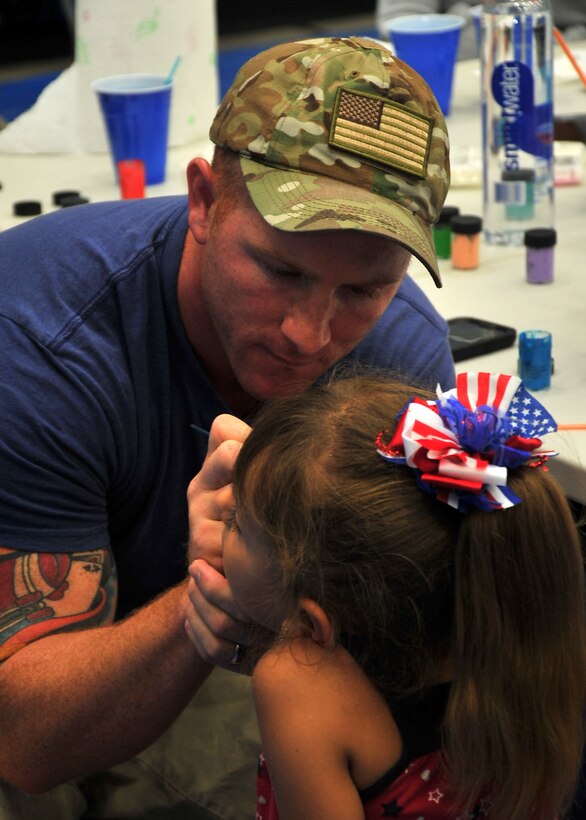 Staff Sgt. William Zenawick, 36th Civil Engineer Squadron, paints a child’s face during the Freedom Fest event July 4, 2014, on Andersen Air Force Base, Guam. Wallyball and pingpong tournaments, face painting, and watermelon eating contests were some of the events held during Freedom Fest at the Coral Reef Fitness Center in celebration of Independence Day. (U.S. Air Force photo by Staff Sgt. Melissa B. White/Released)