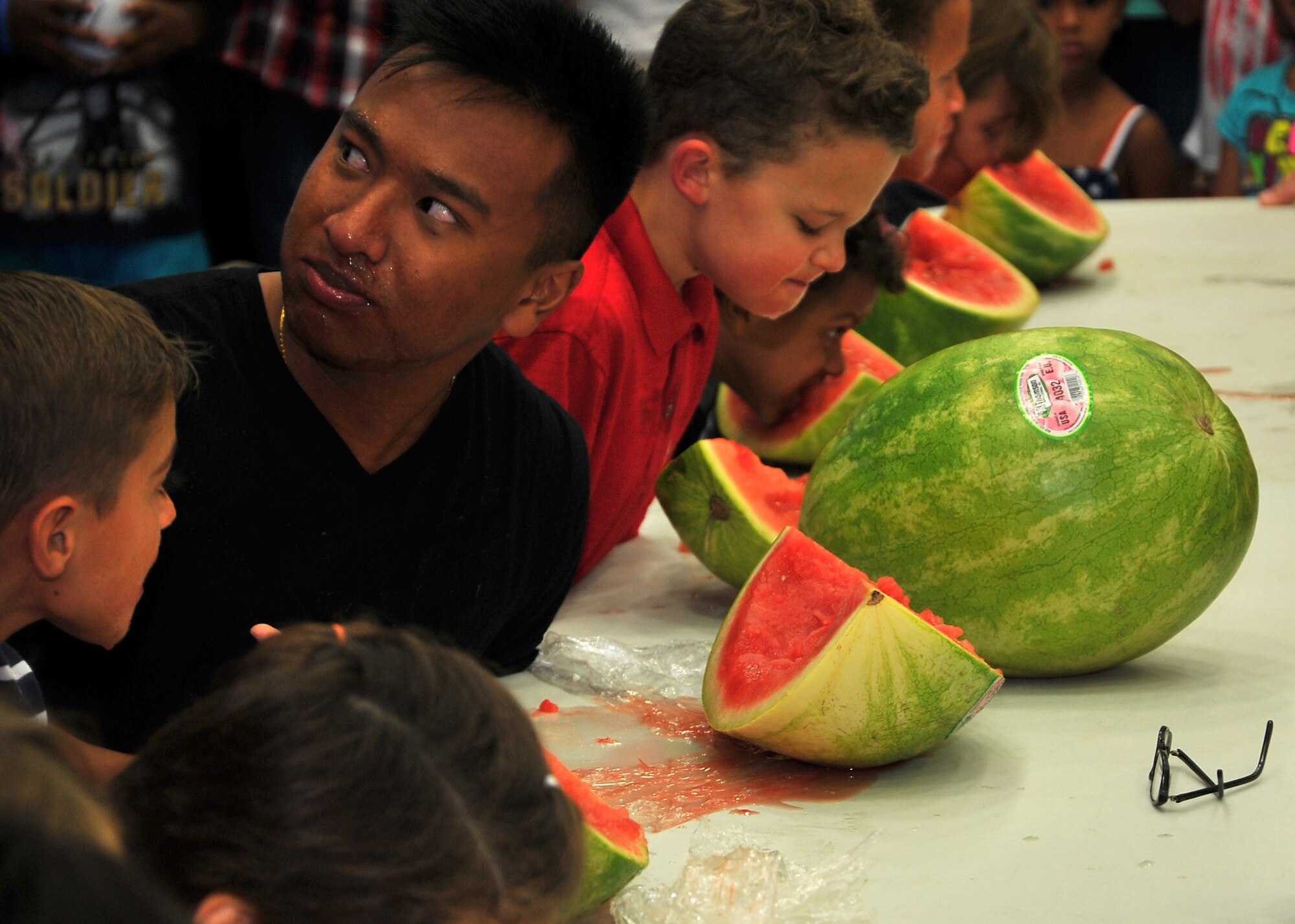Members of Team Andersen participate in a watermelon eating contest at the Freedom Fest event July 4, 2014, on Andersen Air Force Base, Guam. Wallyball and pingpong tournaments, face painting, and watermelon eating contests were some of the events held during Freedom Fest at the Coral Reef Fitness Center in celebration of Independence Day. (U.S. Air Force photo by Staff Sgt. Melissa B. White/Released)