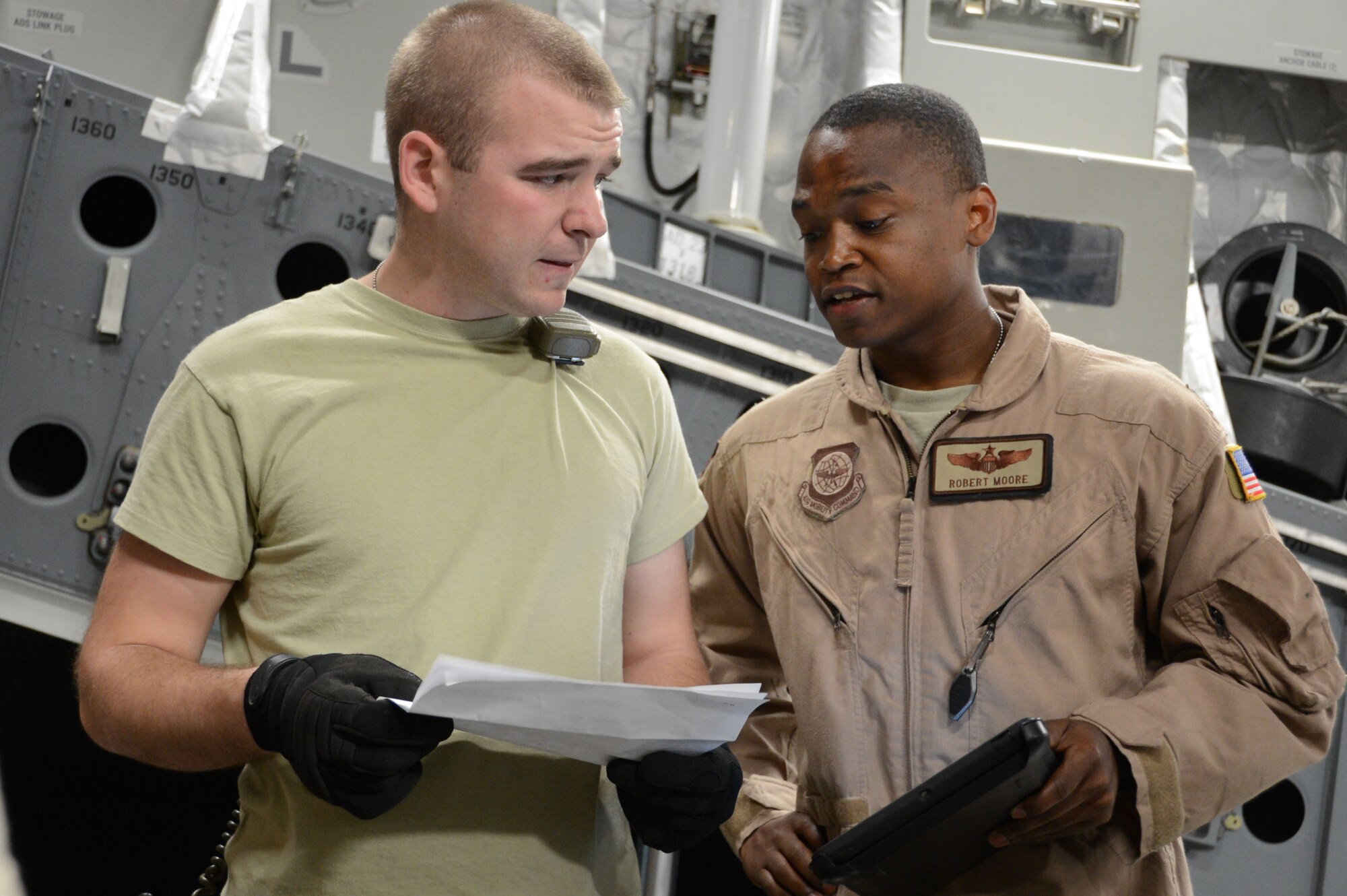 BAGRAM AIRFIELD, Afghanistan – U.S. Air Force Senior Airman Robert Oliver, a cargo processor assigned to the 455th Aerial Port Squadron and a native of Mt. Clemens, Mich. confers with Capt. Robert Moore, a native of Warrensburgh, Mo., and a pilot currently assigned to the 385th Detachment 1, Al Udeid, Qatar about the weight of cargo that will be loaded onto a C-17 Globemaster III at Bagram Airfield, Afghanistan June 21, 2014. Oliver is deployed from the 436th Aerial Port Squadron, Dover Air Force Base, Del. and Moore is deployed from the 8th Airlift Squadron, McChord Air Force Base, Wash. (U.S. Air Force photo by Master Sgt. Cohen A. Young/Released) 