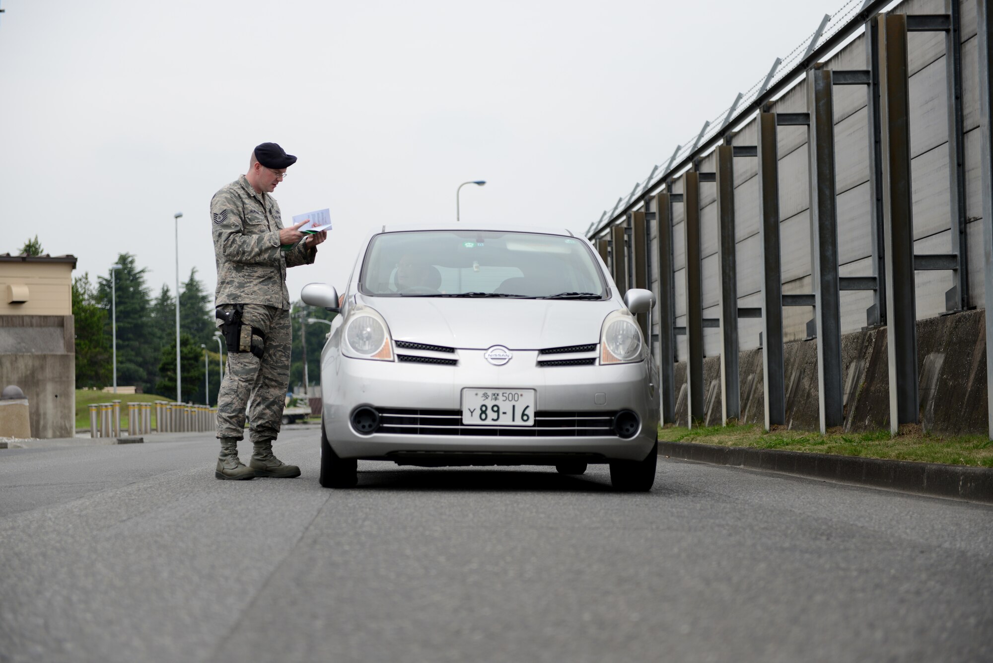 Tech. Sgt. Davy Hoffman, 374th Security Forces Squadron unit resource advisor, checks a driver’s vehicle documents during a traffic safety surge at Yokota Air Base, Japan, July 3, 2014. Hoffman and the other patrolmen were checking drivers for documents, such as current licenses and insurance, at random check points throughout Yokota. (U.S. Air Force photo by U.S. Air Force Staff Sgt. Cody H. Ramirez/Released)