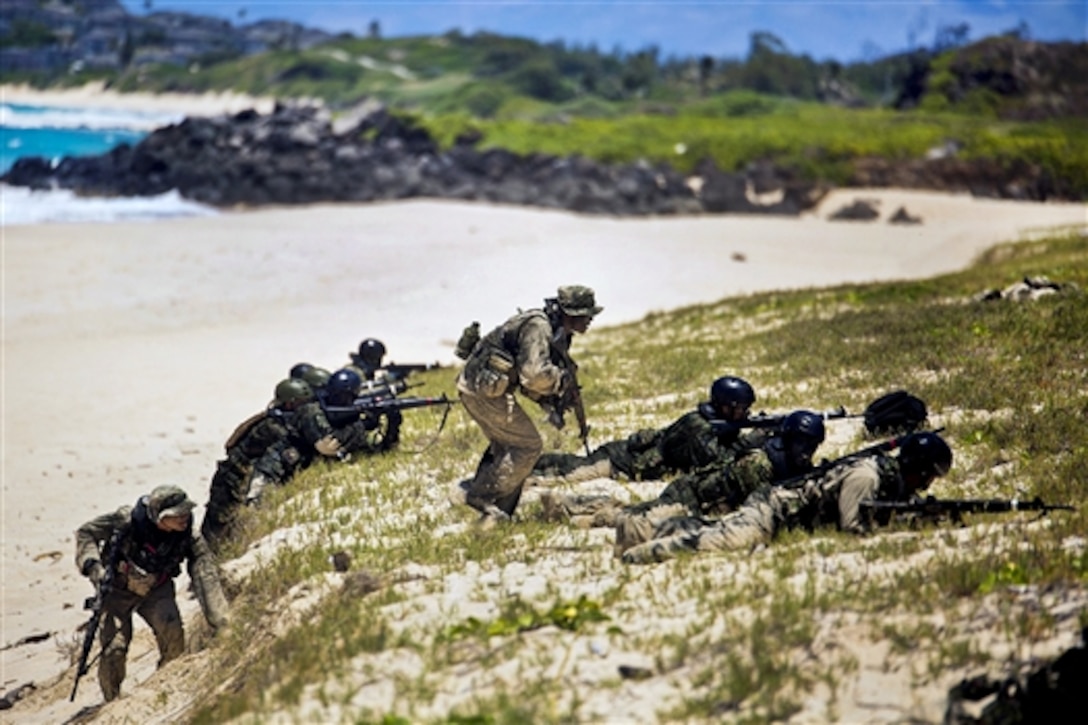 Two Japanese soldiers, left and center, advance as part of an amphibious assault while their squads provide cover during Rim of the Pacific 2014 at Pyramid Rock Beach, Oahu, July 1, 2014. The soldiers trained with U.S. Marines assigned to the 3rd Reconnaissance Battalion based in Okinawa, Japan. The biennial exercise is the world's largest international maritime training event. 