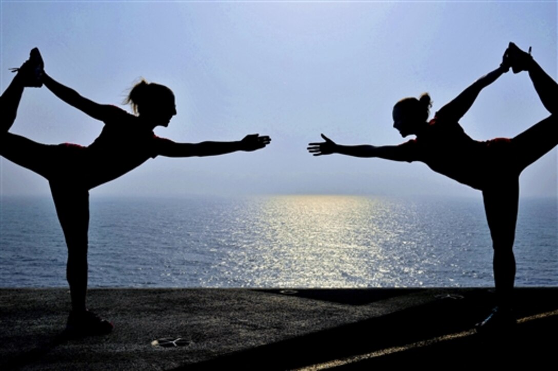 U.S. Navy Lt. Diane Kruse, left, and Lt. Alyse Dason practice yoga poses on the flight deck of the aircraft carrier USS George H.W. Bush in the Arabian Gulf, July 5, 2014. The ship is supporting maritime security operations and theater security cooperation efforts in the U.S. 5th Fleet area of responsibility. 