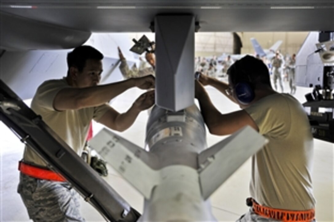 Air Force Staff Sgt. Trung Dinh, left, and Senior Airman Devin Milburn attach a GBU-12 Paveway laser-guided bomb onto an MQ-9 Reaper during a loading competition on Creech Air Force Base, Nev., June 30, 2014. The competition consists of two three-man teams from different aircraft maintenance units competing to build skills and promote camaraderie. Dinh is a 432nd Aircraft Maintenance Squadron weapons load crew chief and Milburn is a 432nd Aircraft Maintenance Squadron support technician.