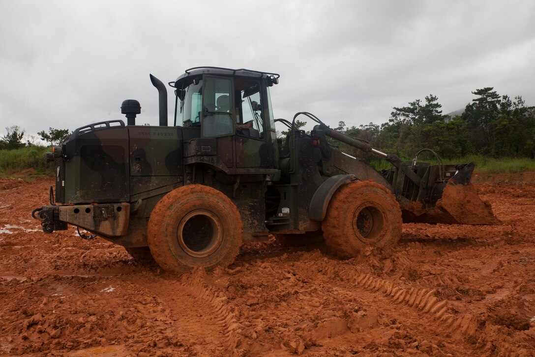 Marines with Combat Logistics Battalion 4, Combat Logistics Regiment 3, execute earth moving procedures with a 120M motorized road grader June 25 during a field exercise at Camp Hansen. The rain was unexpected, but helped them with operating the equipment during inclement weather. The Marines are with CLB-4, CLR-3, 3rd Marine Logistics Group, III Marine Expeditionary Force. (U.S. Marine Corps photo by Lance Cpl. Isaac Ibarra/Released)