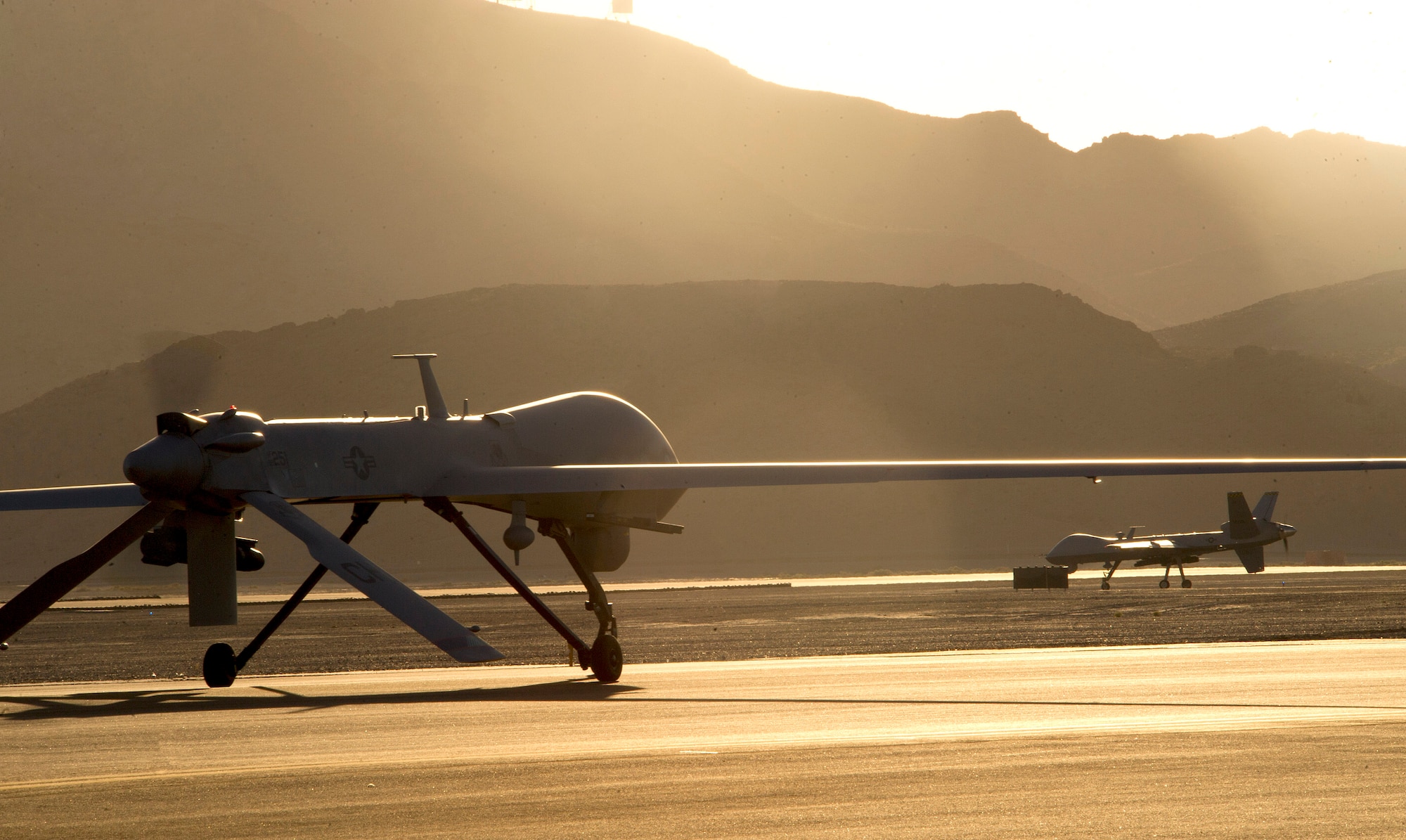An MQ-1B Predator, left, and an MQ-9 Reaper taxi to the runway in preparation for takeoff June 13, 2014, on Creech Air Force Base, Nev. The aircraft are assigned to the 432nd Wing, which trains pilots, sensor operators and other remotely piloted aircraft crewmembers, and conducts combat surveillance and attack operations worldwide. (U.S. Air Force photo/Airman 1st Class Christian Clausen)