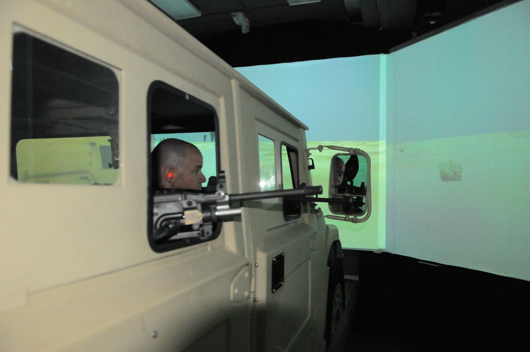 A member from the Employee Reserve Support Group in Rochester, N.Y. takes aim during a mock convoy op this spring at Camp Upshur in the Virtual Convoy Combat Trainer. The VCCT helps simulate combat operations using preinstalled maps of terrain in Iraq.