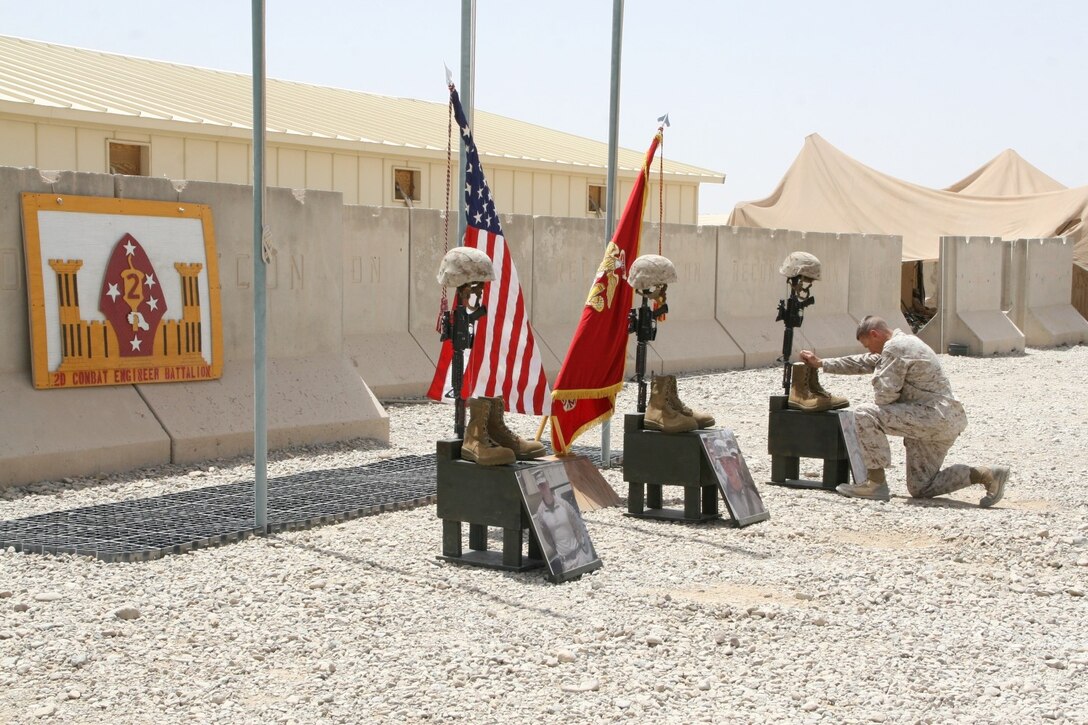 Lieutenant Col. John C. Osborne, commanding officer, 2nd Combat Engineer Battalion, kneels at one of the battlefield crosses to pay his respect to three Marine heroes during a memorial ceremony aboard Camp Leatherneck, Afghanistan, July 8, 2014. Three battlefield crosses stand honoring, from left to right, Staff Sgt. David H. Stewart, a combat engineer, platoon sergeant and native of Stafford, Virginia; Cpl. Brandon J. Garabrant, a combat engineer and native of Peterborough, New Hampshire; and Cpl. Adam F. Wolff, a combat engineer and native of Cedar Rapids, Iowa, all Marines serving with 3rd Platoon, Route Clearance Company, 2nd CEB, who gave the ultimate sacrifice while conducting combat operations in Helmand province, Afghanistan, June 20, 2014.