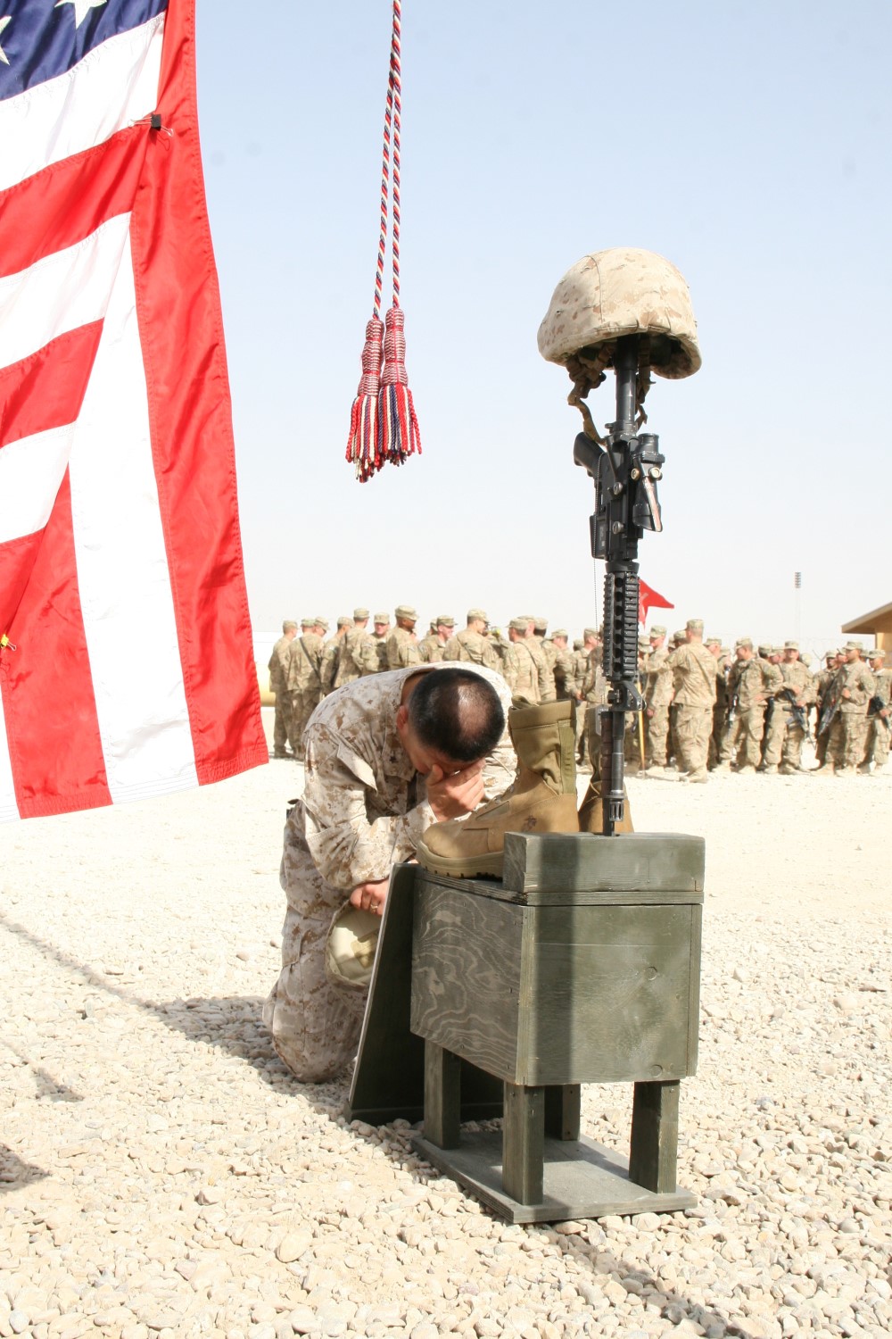 Brigadier Gen. Daniel D. Yoo, commander, Regional Command (Southwest), kneels at one of the battlefield crosses to pay his respect to three Marine heroes during a memorial ceremony aboard Camp Leatherneck, Afghanistan, July 8, 2014. Three battlefield crosses stand in honor of Staff Sgt. David H. Stewart, a combat engineer, platoon sergeant and native of Stafford, Virginia; Cpl. Brandon J. Garabrant, a combat engineer and native of Peterborough, New Hampshire; and Cpl. Adam F. Wolff, a combat engineer and native of Cedar Rapids, Iowa, all Marines serving with 3rd Platoon, Route Clearance Company, 2nd CEB, who gave the ultimate sacrifice while conducting combat operations in Helmand province, Afghanistan, June 20, 2014.