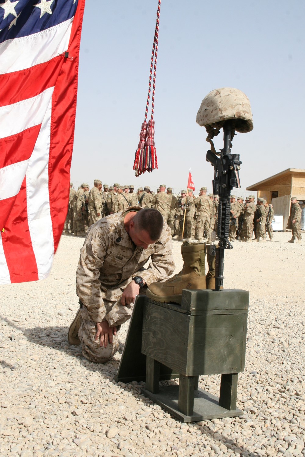 Sergeant Maj. Douglas E. Berry Jr., sergeant major, Regional Command (Southwest), kneels at one of the battlefield crosses to pay his respect to three Marine heroes during a memorial ceremony aboard Camp Leatherneck, Afghanistan, July 8, 2014. Three battlefield crosses stand in honor of Staff Sgt. David H. Stewart, a combat engineer, platoon sergeant and native of Stafford, Virginia; Cpl. Brandon J. Garabrant, a combat engineer and native of Peterborough, New Hampshire; and Cpl. Adam F. Wolff, a combat engineer and native of Cedar Rapids, Iowa, all Marines serving with 3rd Platoon, Route Clearance Company, 2nd CEB, who gave the ultimate sacrifice while conducting combat operations in Helmand province, Afghanistan, June 20, 2014.