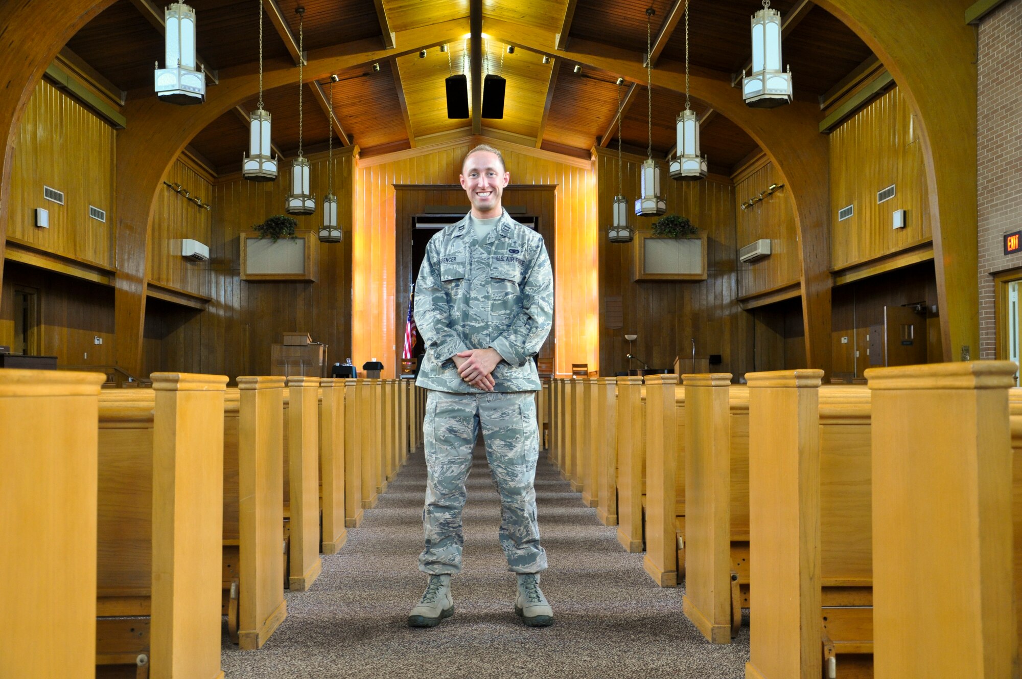 Captain Matthew Spencer, 325th Fighter Wing chaplain, stands between the pews in Chapel 2 at Tyndall Air Force Base July 3. 2014. Spencer was a prior enlisted member of security forces before he commissioned as an officer and became a chaplain in the Air Force Reserve. (U.S. Air Force photo by 2nd Lt. Christopher Bowyer-Meeder)