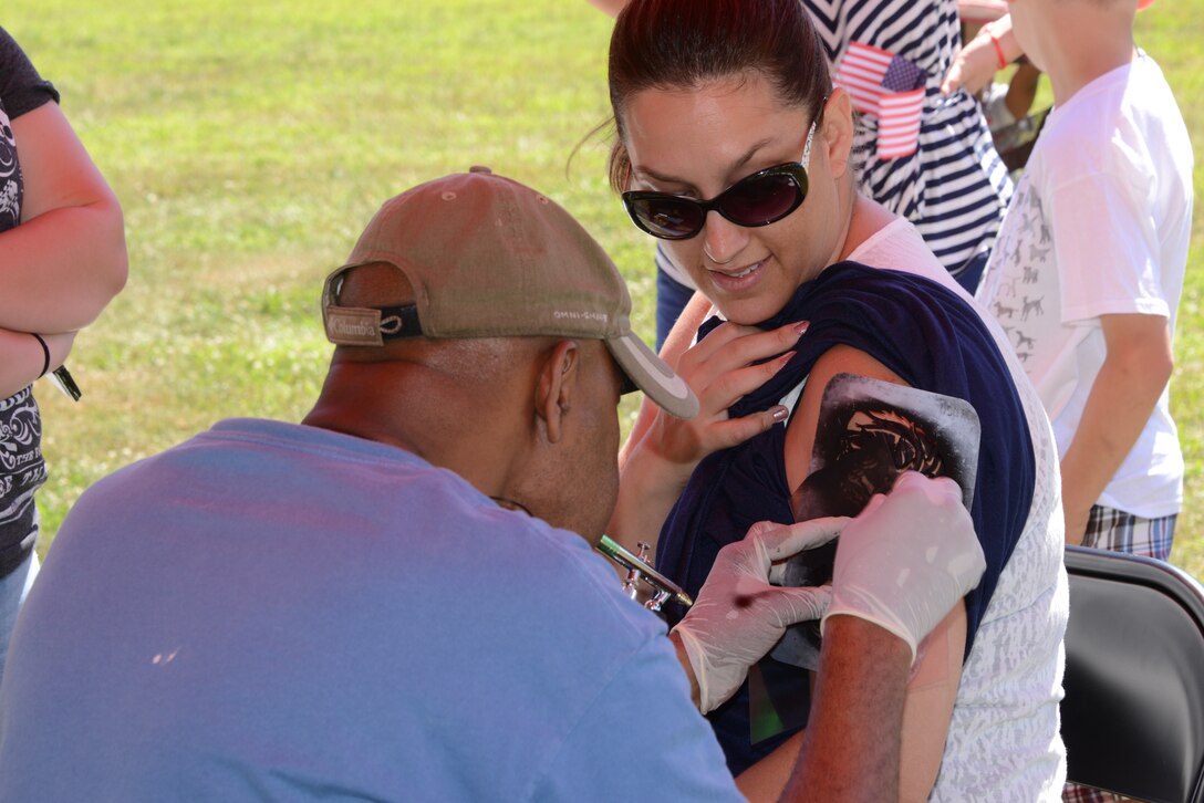 Mellissa Matuewezski, participant, gets a temporary airbrush tattoo at the Independence Day Celebration on Lejeune Field July 4, 2014. In addition to the temporary tattoo artist, there was a moon bounce, inflatable obstacle course, rock wall, food vendors and a live, local band at the celebration.  