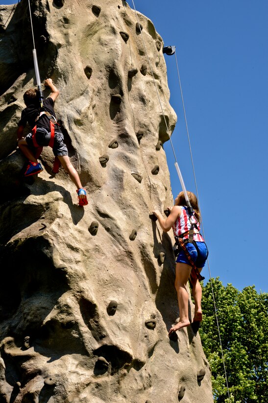 Caleb, 7, and Abby, 10, siblings,  race to the top of the rock wall during the Independence Day celebration on Lejeune Field July 4, 2014. DOD cardholders and their guests started gathering for the festivities at 3 p.m. (U.S. Marine Corps photo by Sgt. Rebekka S. Heite/Released)