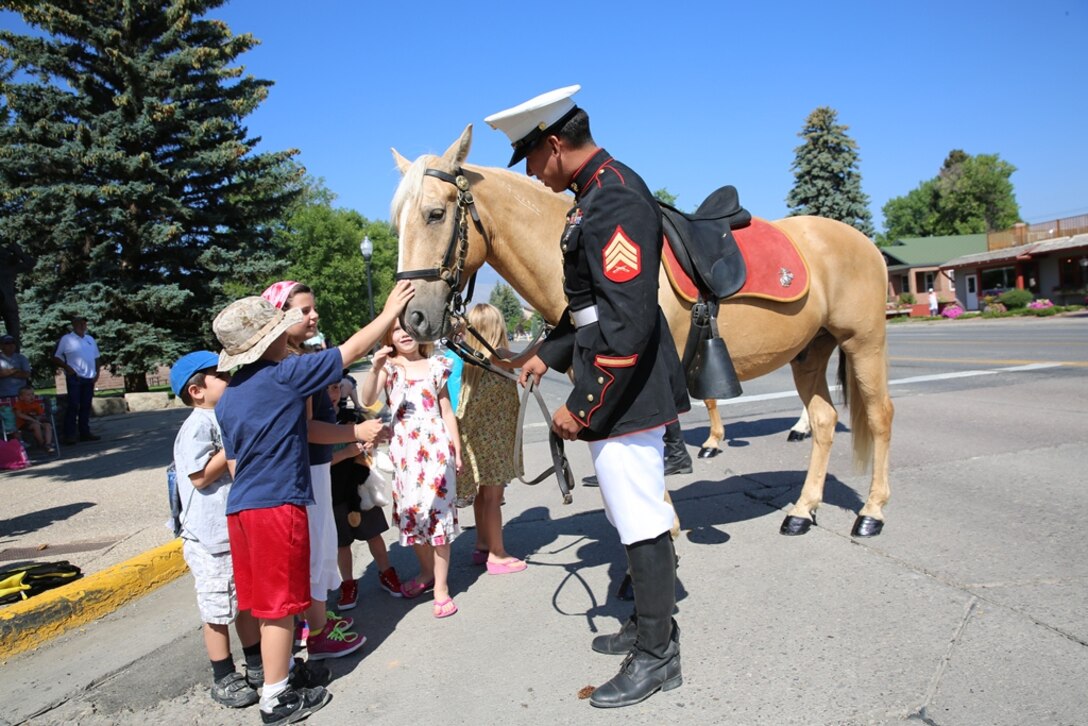 Sgt Moises Machuca,(Above) stableman with the Marine Corps Mounted Color Guard on Marine Corps Logistics Base Barstow, Calif., lets children pet his horse, Reno, during the Kiddy Parade in Cody, Wyo., July 2.