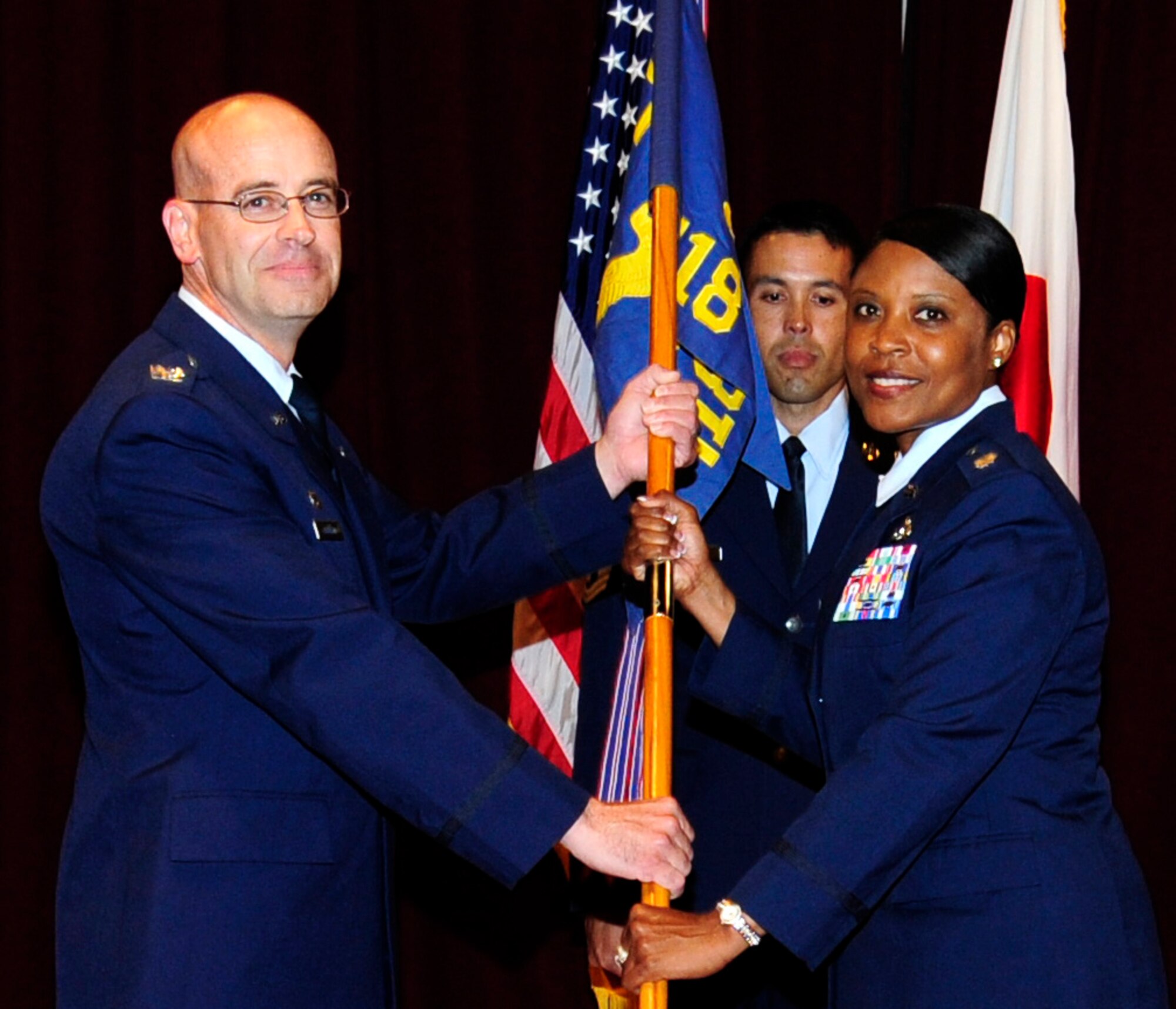 U.S. Air Force Col. Dwayne Robison, 18th Civil Engineer Group commander, passes the guidon to Lt. Col Tanya Anderson, 718th Civil Engineer Squadron commander, during the 718th CES change of command ceremony on Kadena Air Base, Japan, July 11, 2014. Anderson comes from Altus, Oklahoma, where she served as the commander of the 97th CES; providing oversight for the planning, construction, repair, maintenance, operation and management of land facilities, utility contracts and other services.  (U.S. Air Force photo by Airman 1st Class Keith James)