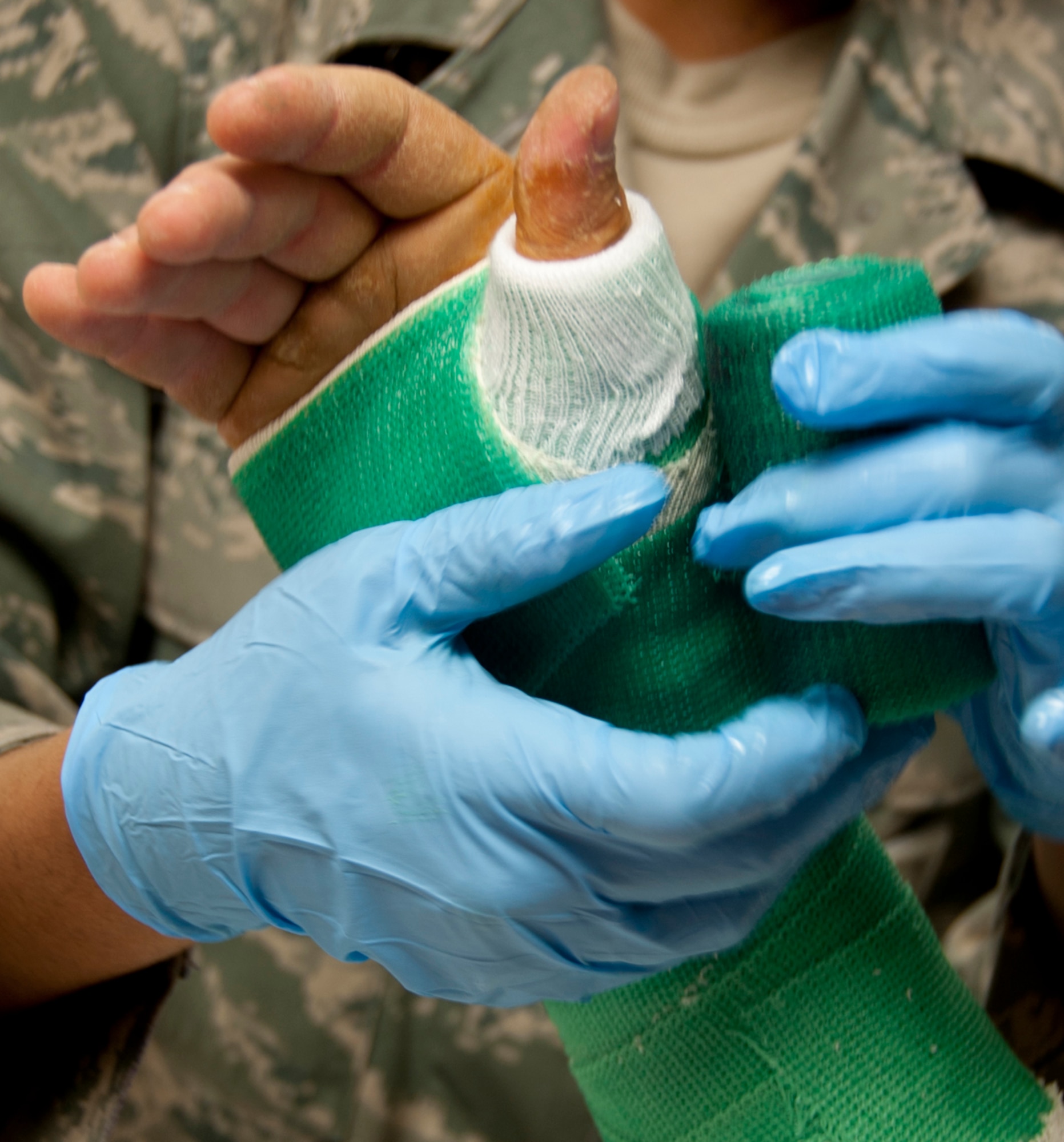 Senior Airman Jessica Stoudmire, 673d Orthopedic and Podiatric Clinic orthopedic technician, wraps casting tape around a patients’ wrist on Joint Base Elmendorf-Richardson July 10. Stoudmire uses a stockinette and webroll under the casting tape to separate the patients’ skin from the cast. (U.S. Air Force photo/Airman 1st Class Tammie Ramsouer)